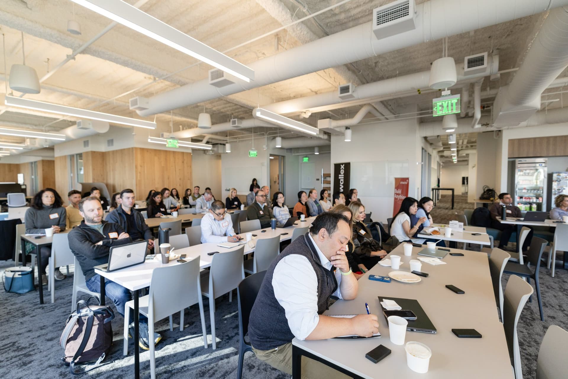 Finance leaders listening at long tables with the Airwallex banner in the background at Airwallex's Beyond the Hype: AI and the Future of Finance breakfast fireside chat at the Airwallex San Francisco office by JY Studio