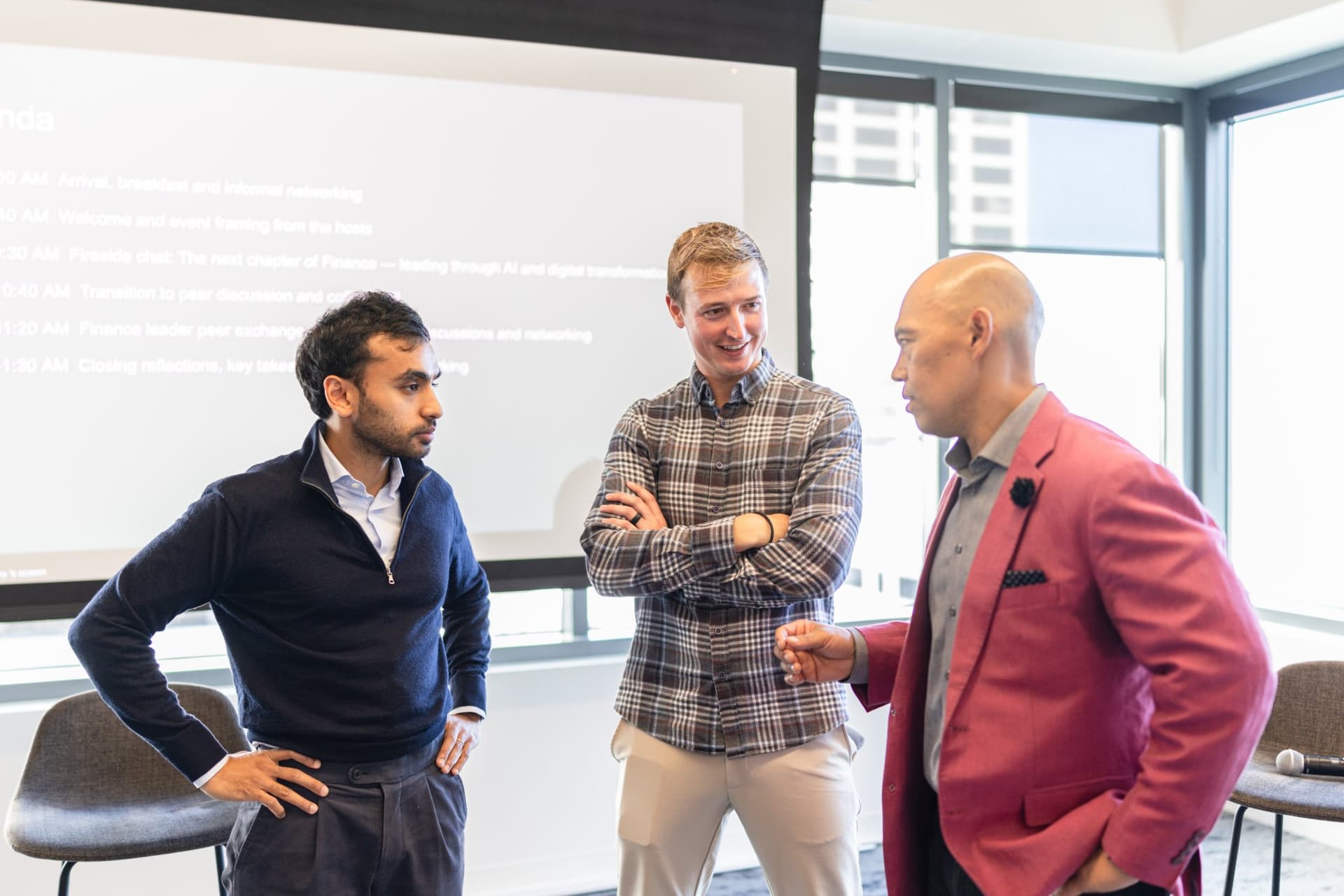 Pranav Sood, Drew Armanino, and Dean Quiambao chatting in front of the agenda slide at Airwallex's Beyond the Hype: AI and the Future of Finance breakfast fireside chat at the Airwallex San Francisco office by JY Studio