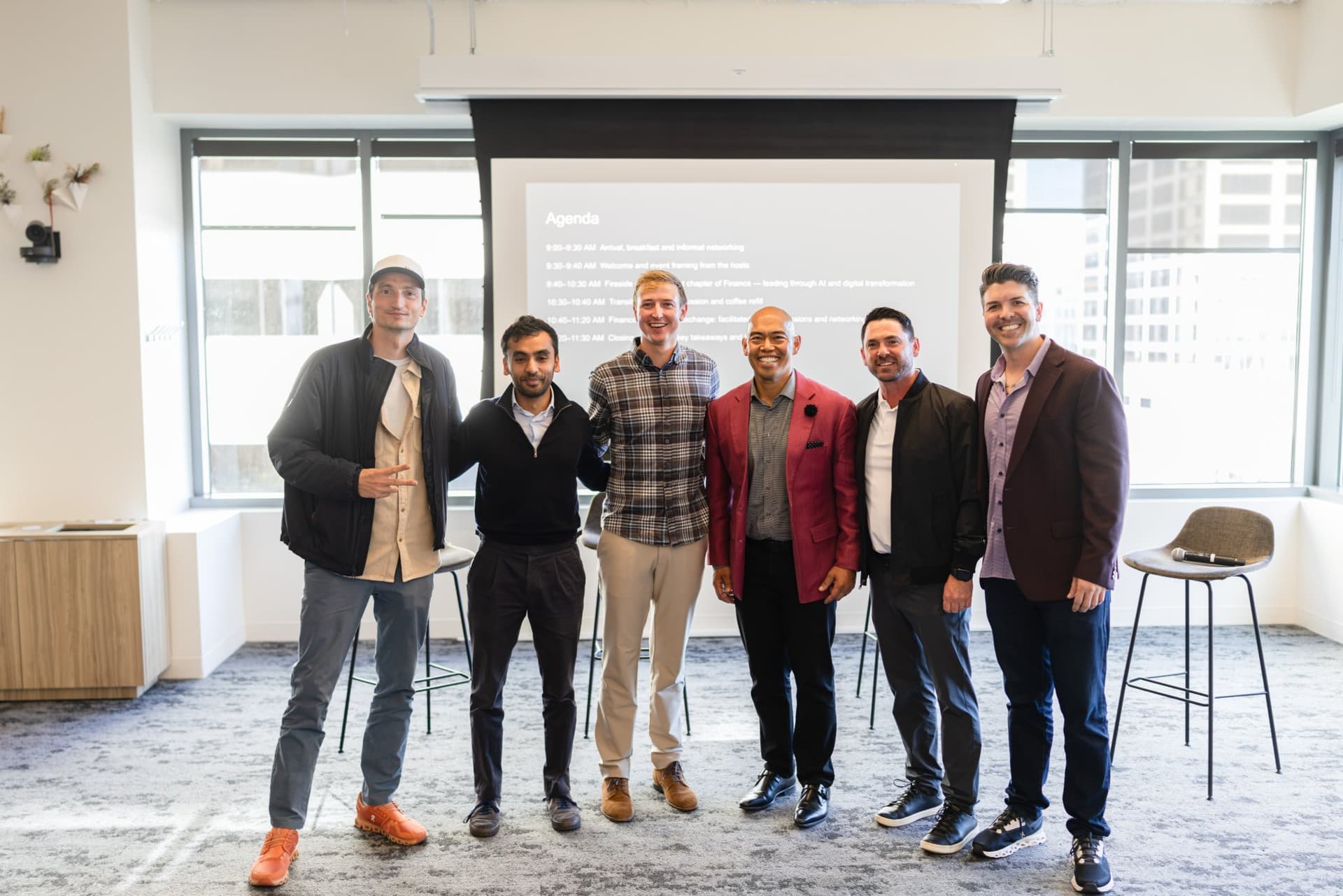 Wide group photo of speakers and hosts in front of the agenda slide at Airwallex's Beyond the Hype: AI and the Future of Finance breakfast fireside chat at the Airwallex San Francisco office by JY Studio
