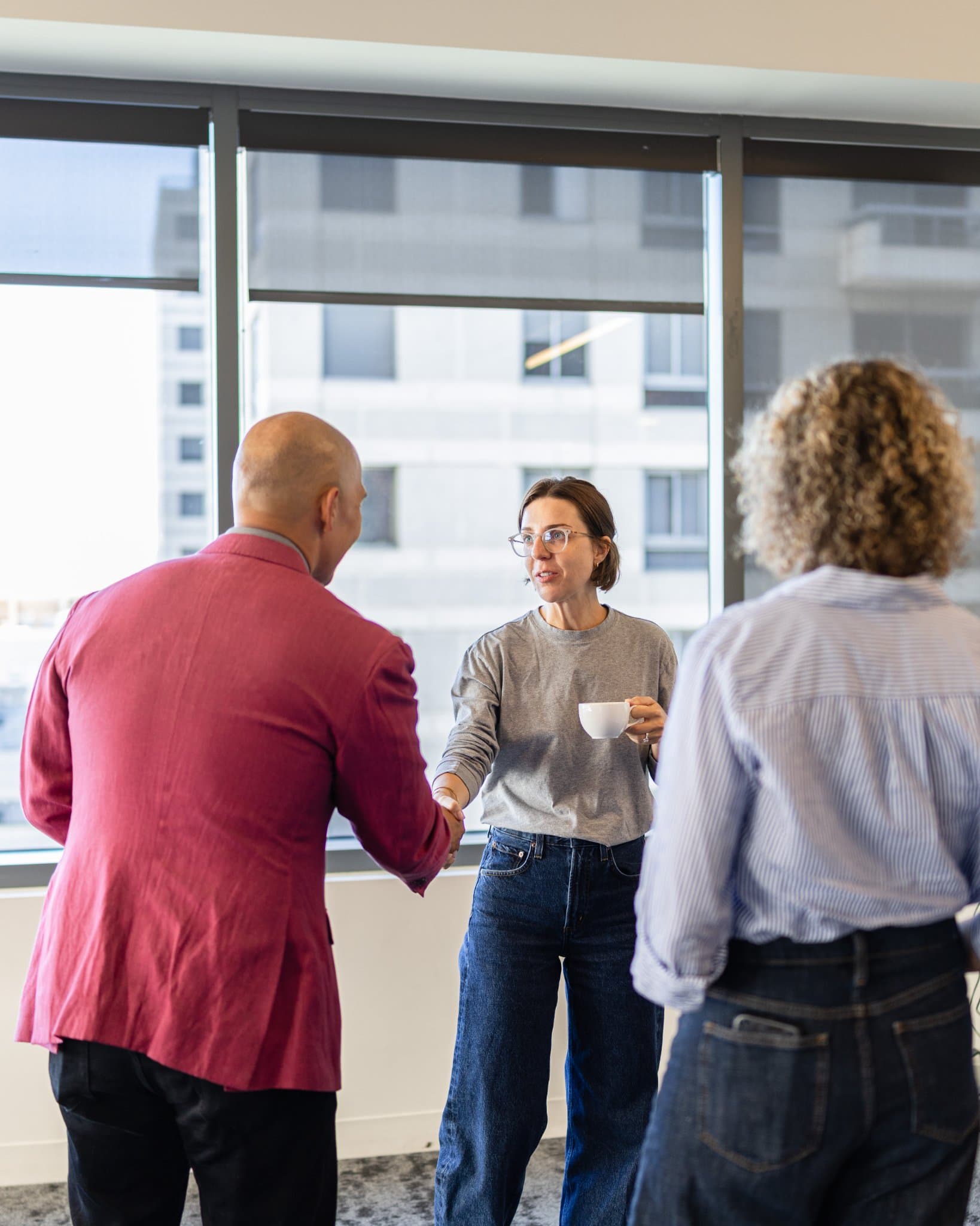 Dean Quiambao welcoming a guest with a handshake at Airwallex's Beyond the Hype: AI and the Future of Finance breakfast fireside chat at the Airwallex San Francisco office by JY Studio