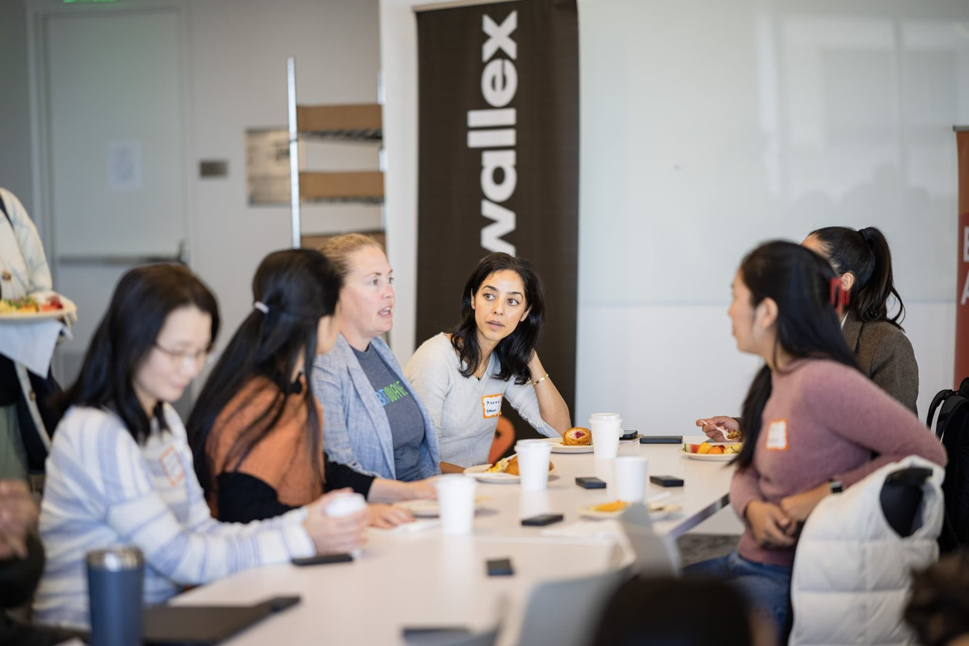 Peer exchange discussion at a table beside the Airwallex banner at Airwallex's Beyond the Hype: AI and the Future of Finance breakfast fireside chat at the Airwallex San Francisco office by JY Studio