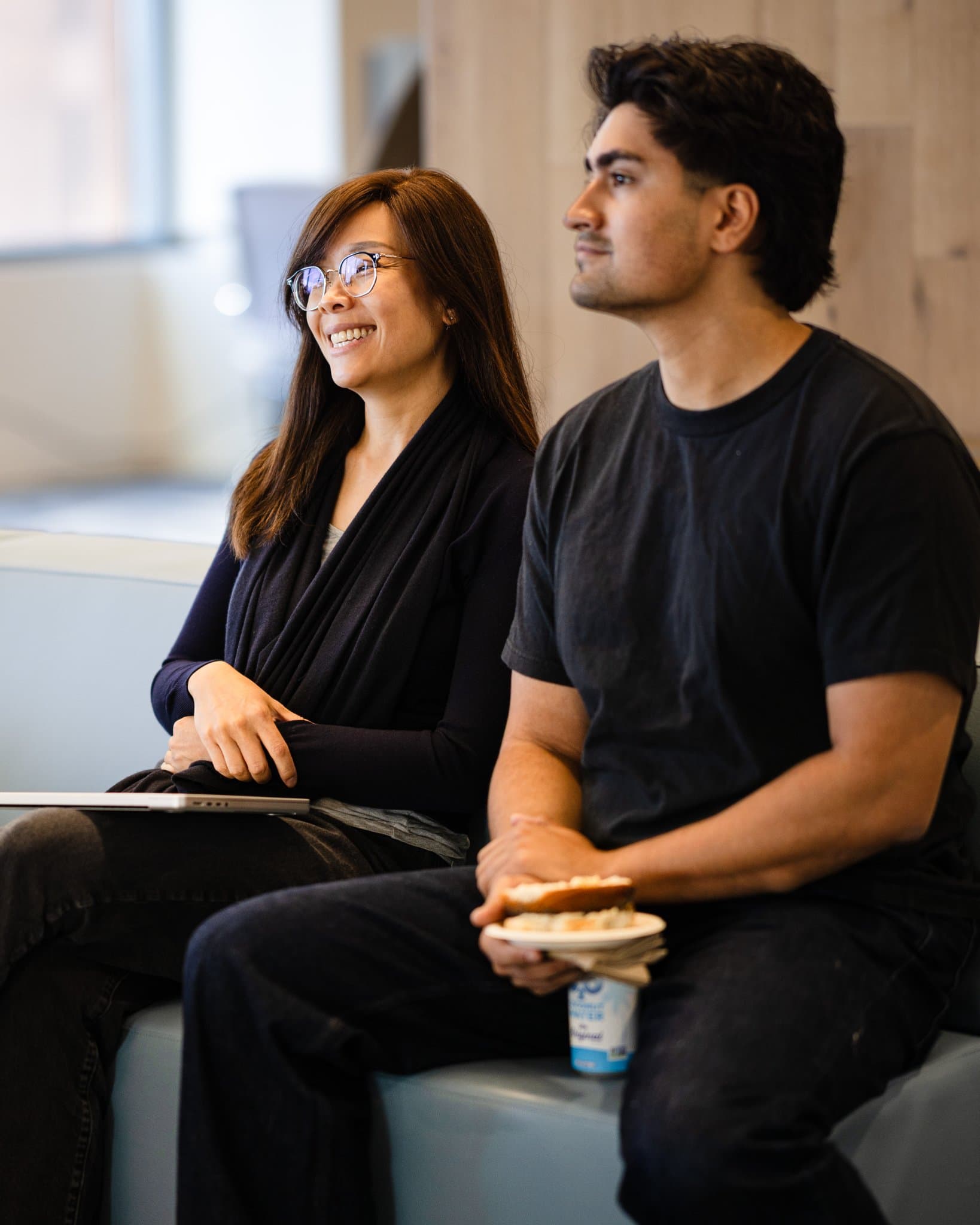 Two attendees smiling while listening to the panel at Airwallex's Beyond the Hype: AI and the Future of Finance breakfast fireside chat at the Airwallex San Francisco office by JY Studio