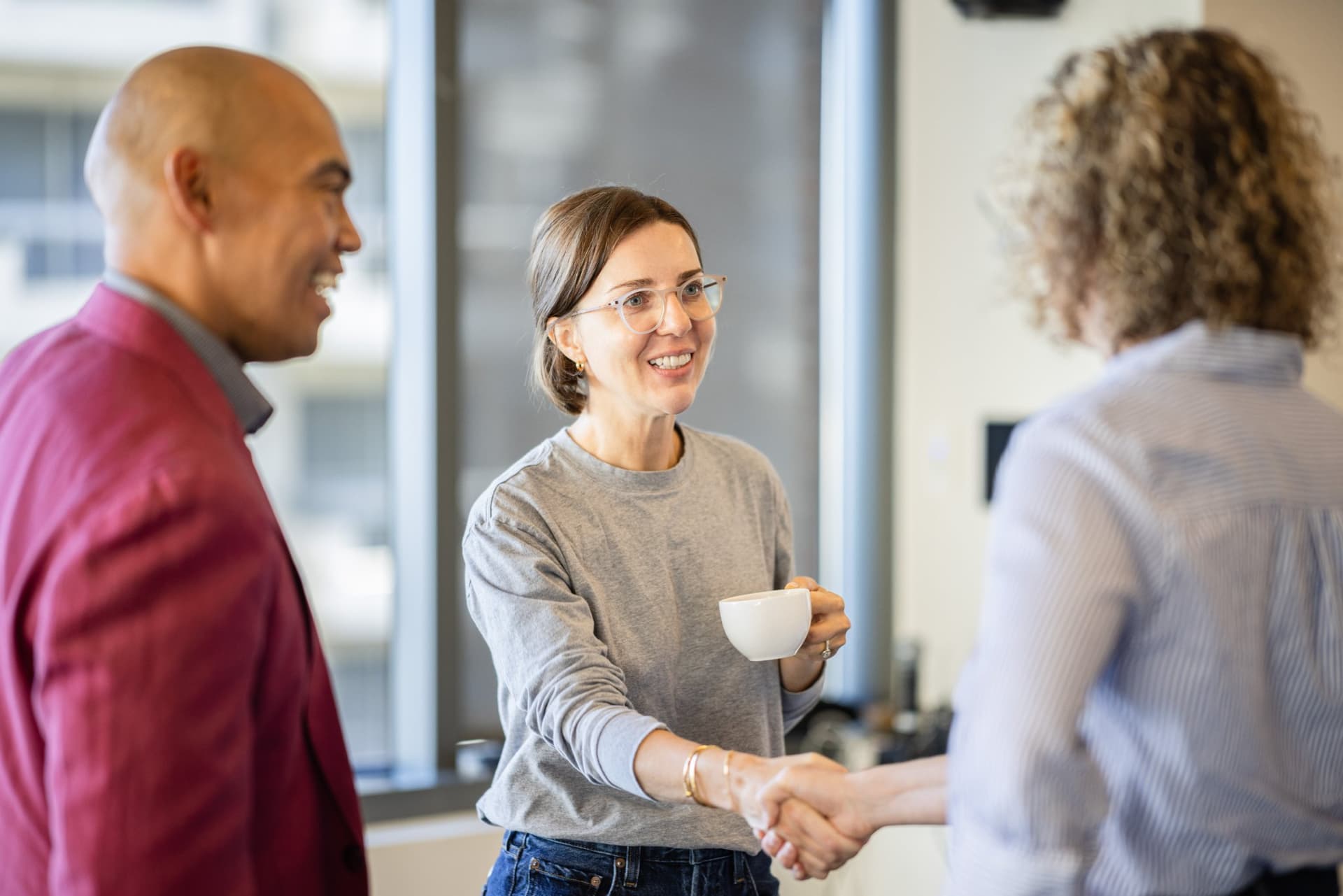 Dean Quiambao shaking hands with a guest at Airwallex's Beyond the Hype: AI and the Future of Finance breakfast fireside chat at the Airwallex San Francisco office by JY Studio