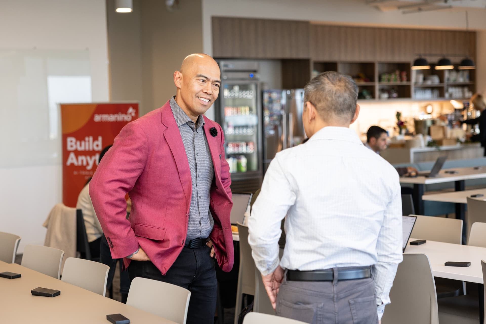 Dean Quiambao greeting an attendee beside the Armanino banner at Airwallex's Beyond the Hype: AI and the Future of Finance breakfast fireside chat at the Airwallex San Francisco office by JY Studio