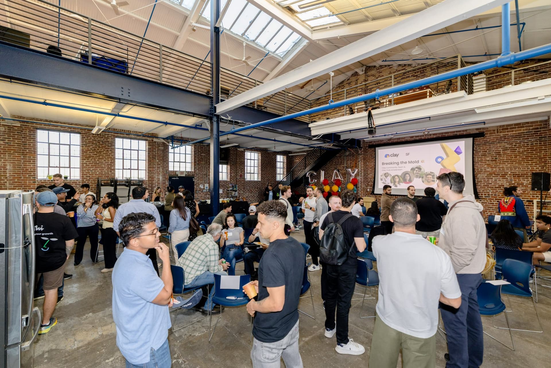 Guests mingling across the brick-and-steel warehouse event space at Clay's Breaking the Mold community networking event during SF Tech Week 2026 in San Francisco by JY Studio