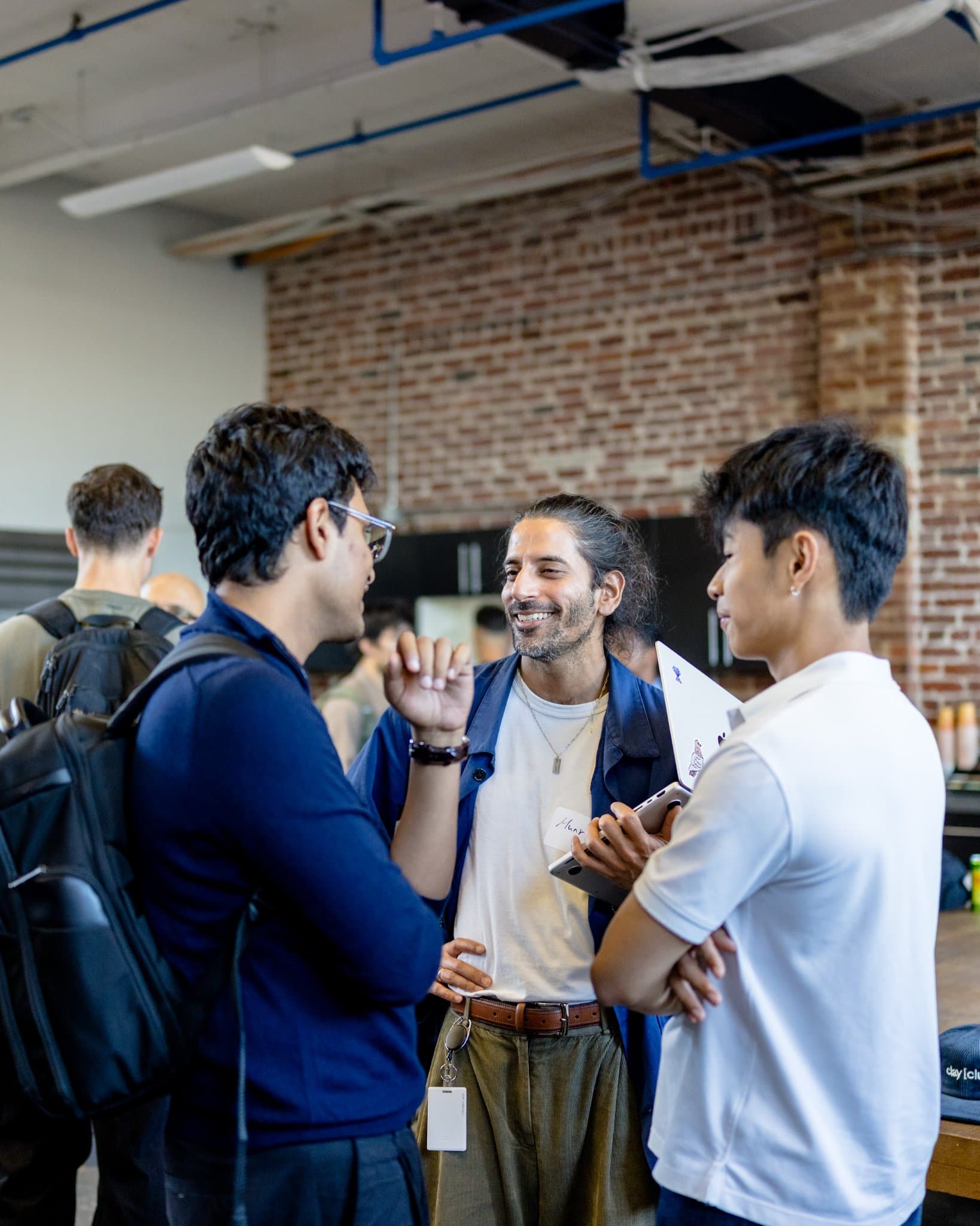 Three guests in animated conversation in the makerspace at Clay's Breaking the Mold community networking event during SF Tech Week 2026 in San Francisco by JY Studio