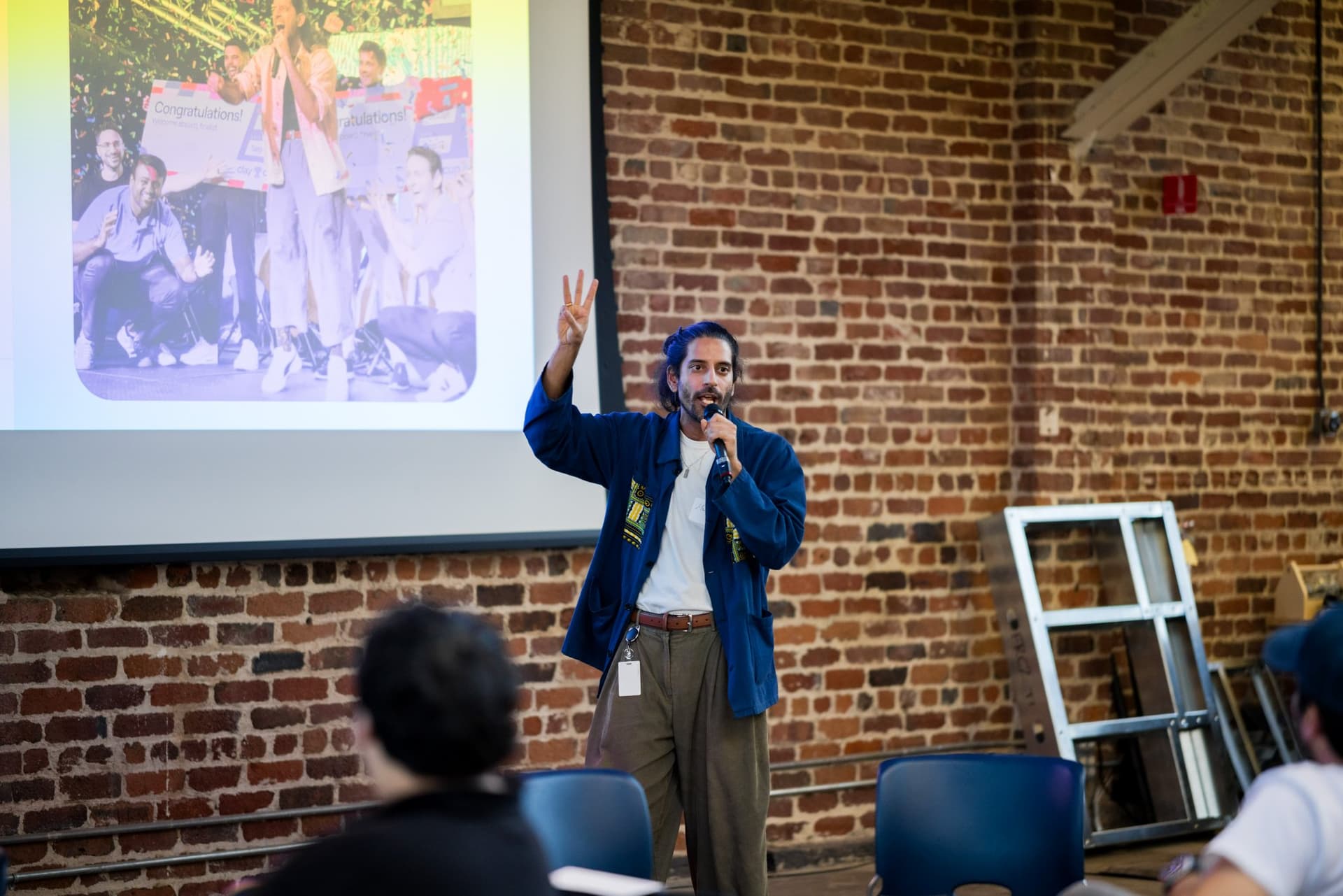 Speaker with a microphone celebrating two years of Clay Club at Clay's Breaking the Mold community networking event during SF Tech Week 2026 in San Francisco by JY Studio