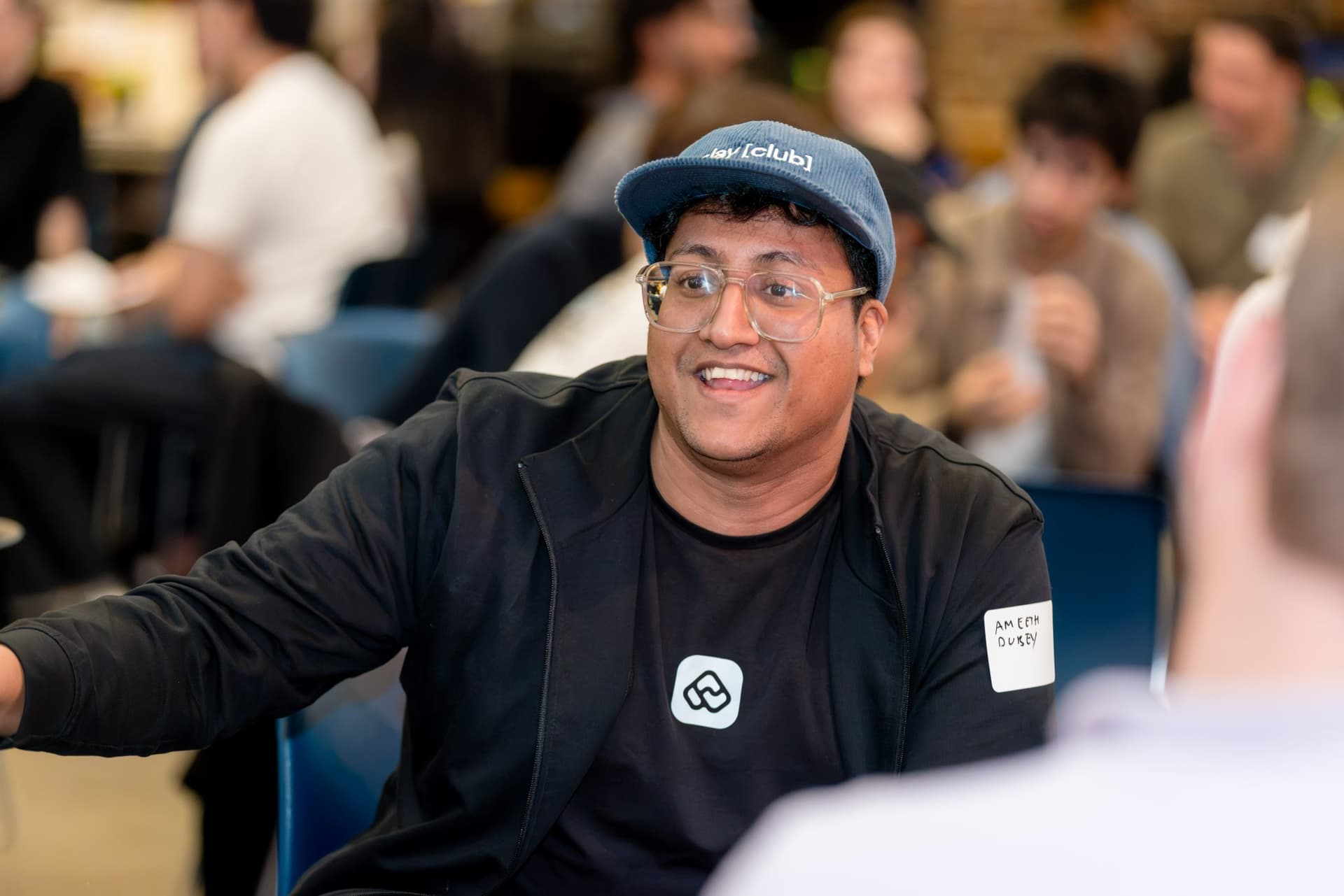 Smiling attendee in a Clay Club cap during the group discussion at Clay's Breaking the Mold community networking event during SF Tech Week 2026 in San Francisco by JY Studio