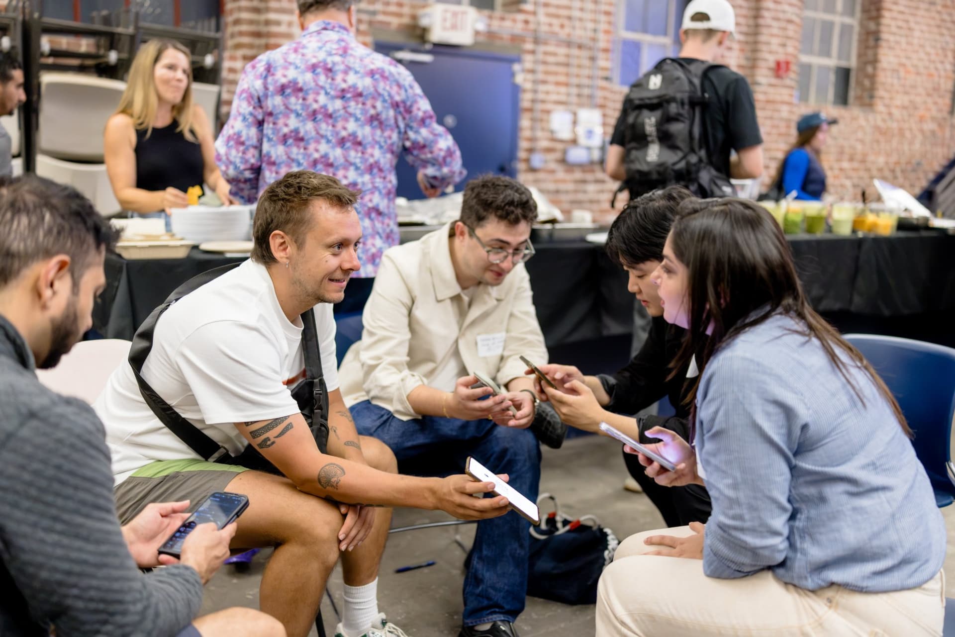 Small group sharing ideas on their phones mid-discussion at Clay's Breaking the Mold community networking event during SF Tech Week 2026 in San Francisco by JY Studio