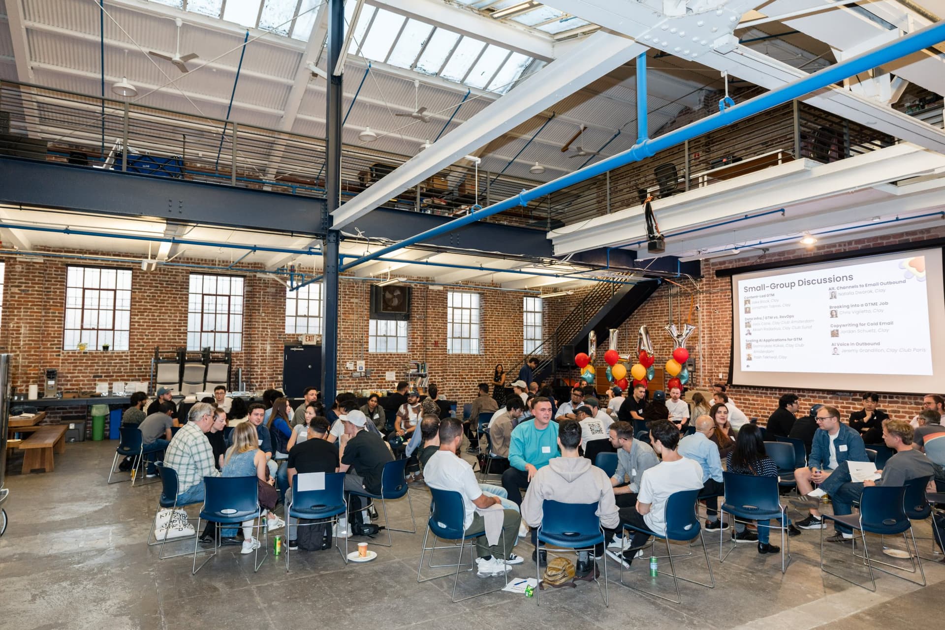 Wide shot of the crowd in discussion circles under the skylights at Clay's Breaking the Mold community networking event during SF Tech Week 2026 in San Francisco by JY Studio