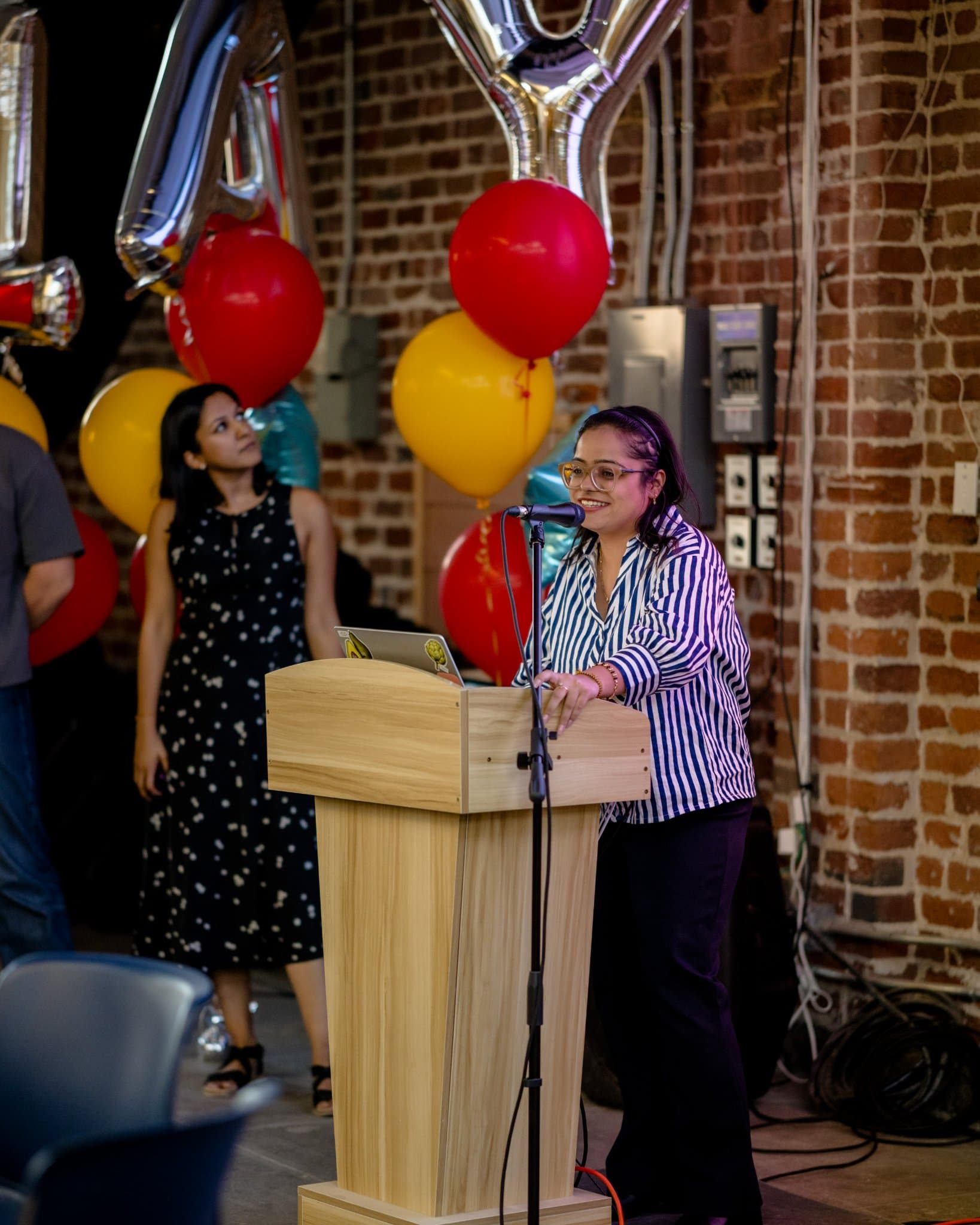 Host speaking at the podium during closing remarks at Clay's Breaking the Mold community networking event during SF Tech Week 2026 in San Francisco by JY Studio