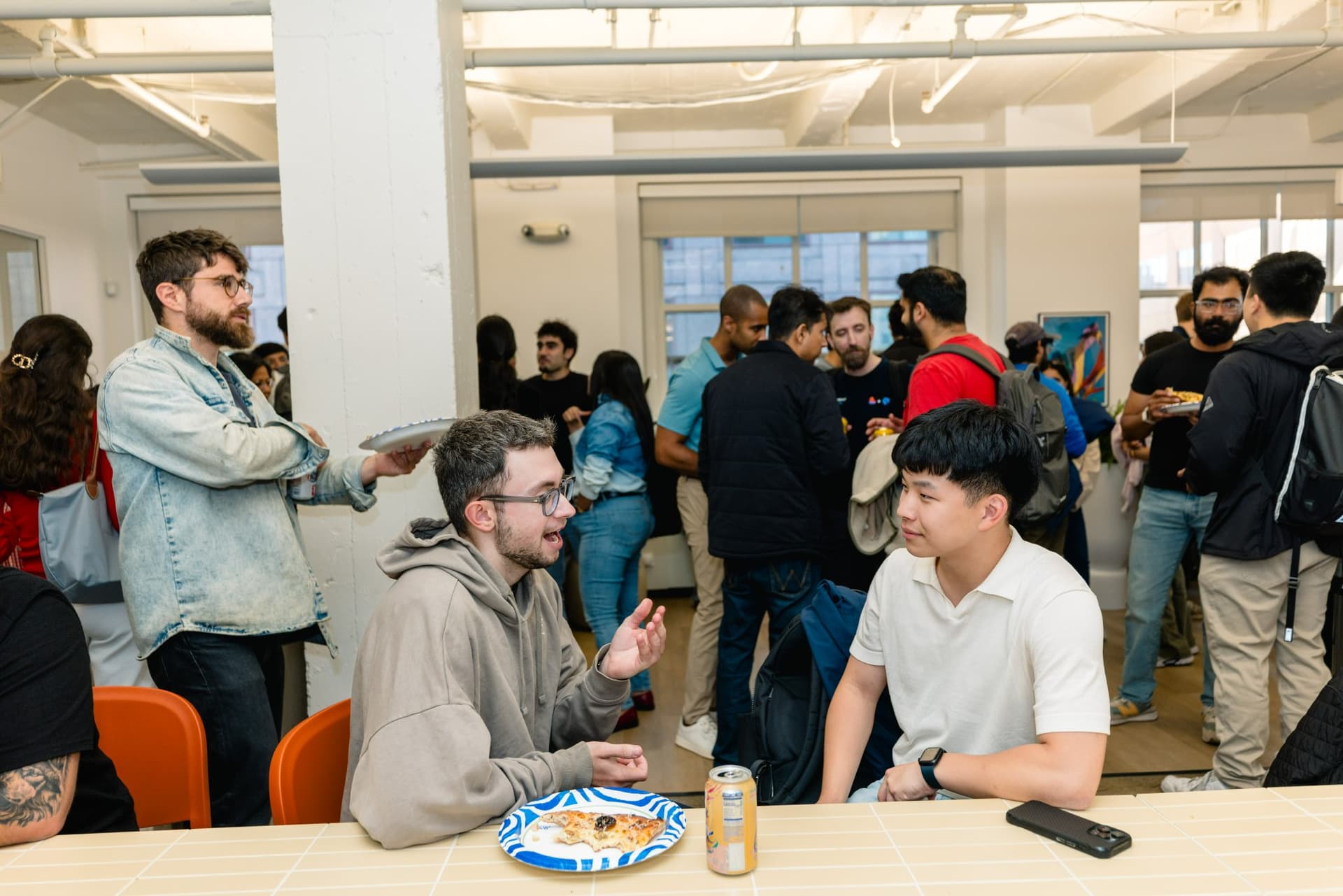 Guests seated on folding chairs with the San Francisco skyline visible through the office windows