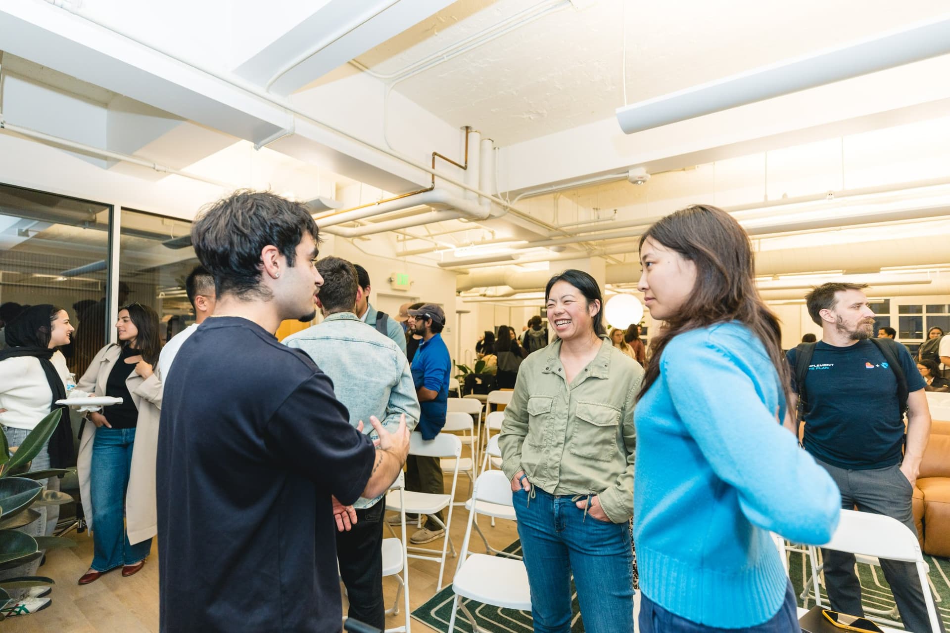 Attendees exchanging introductions near the standing desks at Gumloop's San Francisco office