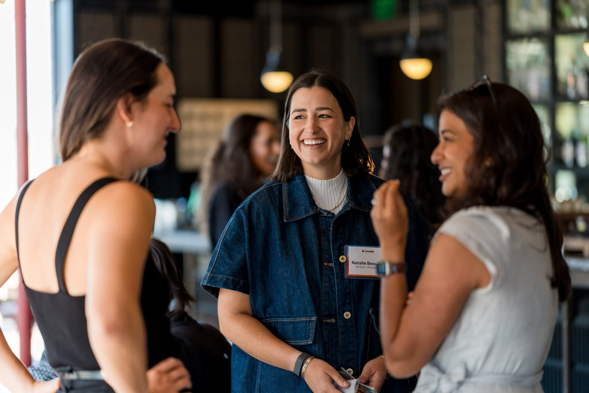 Three guests in conversation during the welcome mingle at Lovable x Wispr Flow's Built on Her Terms brunch roundtable during SF Tech Week 2026 in San Francisco by JY Studio