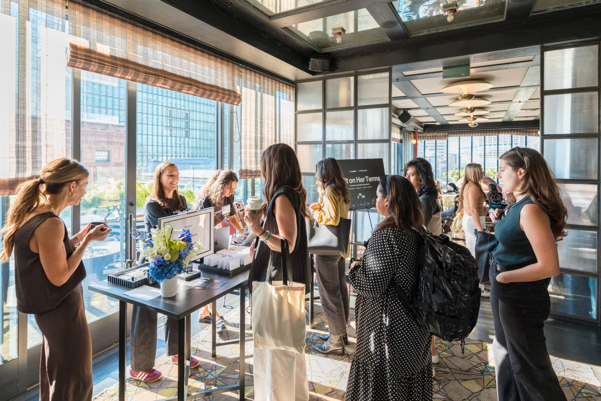 Guests picking up name tags at the sunlit check-in table at Lovable x Wispr Flow's Built on Her Terms brunch roundtable during SF Tech Week 2026 in San Francisco by JY Studio