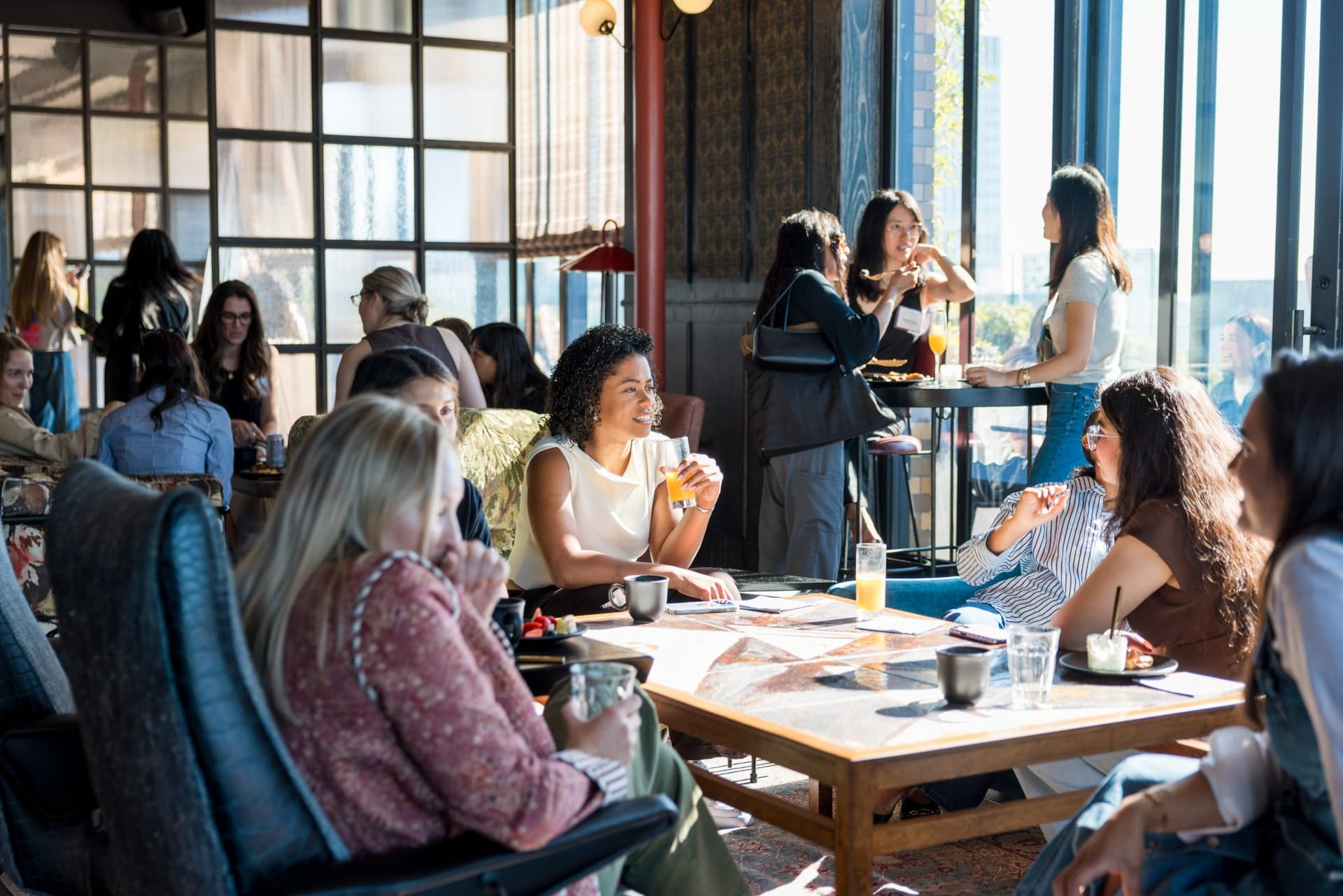 Guests chatting over mimosas and coffee in the lounge seating area at Lovable x Wispr Flow's Built on Her Terms brunch roundtable during SF Tech Week 2026 in San Francisco by JY Studio