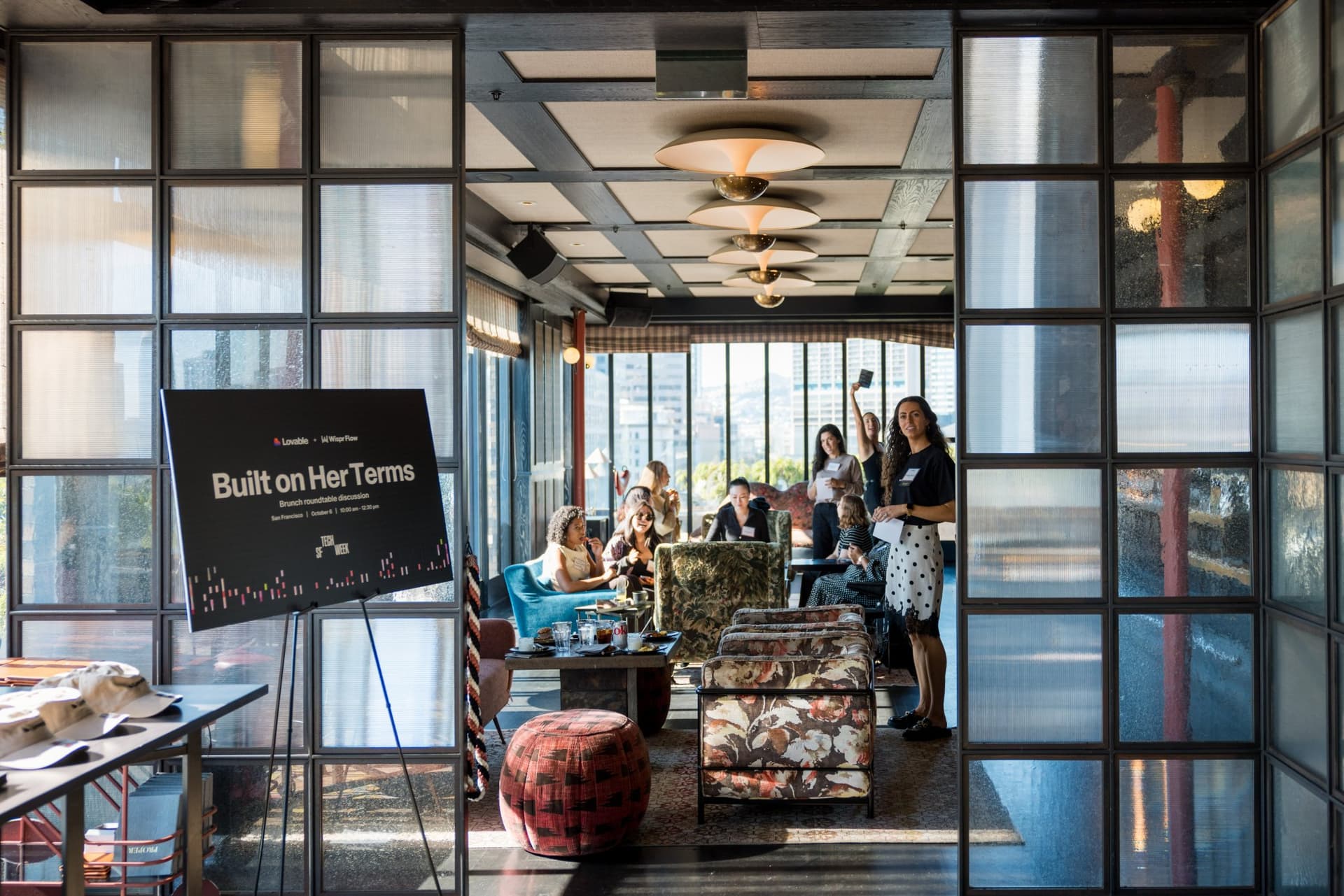 Built on Her Terms sign on an easel overlooking the lounge at Lovable x Wispr Flow's Built on Her Terms brunch roundtable during SF Tech Week 2026 in San Francisco by JY Studio