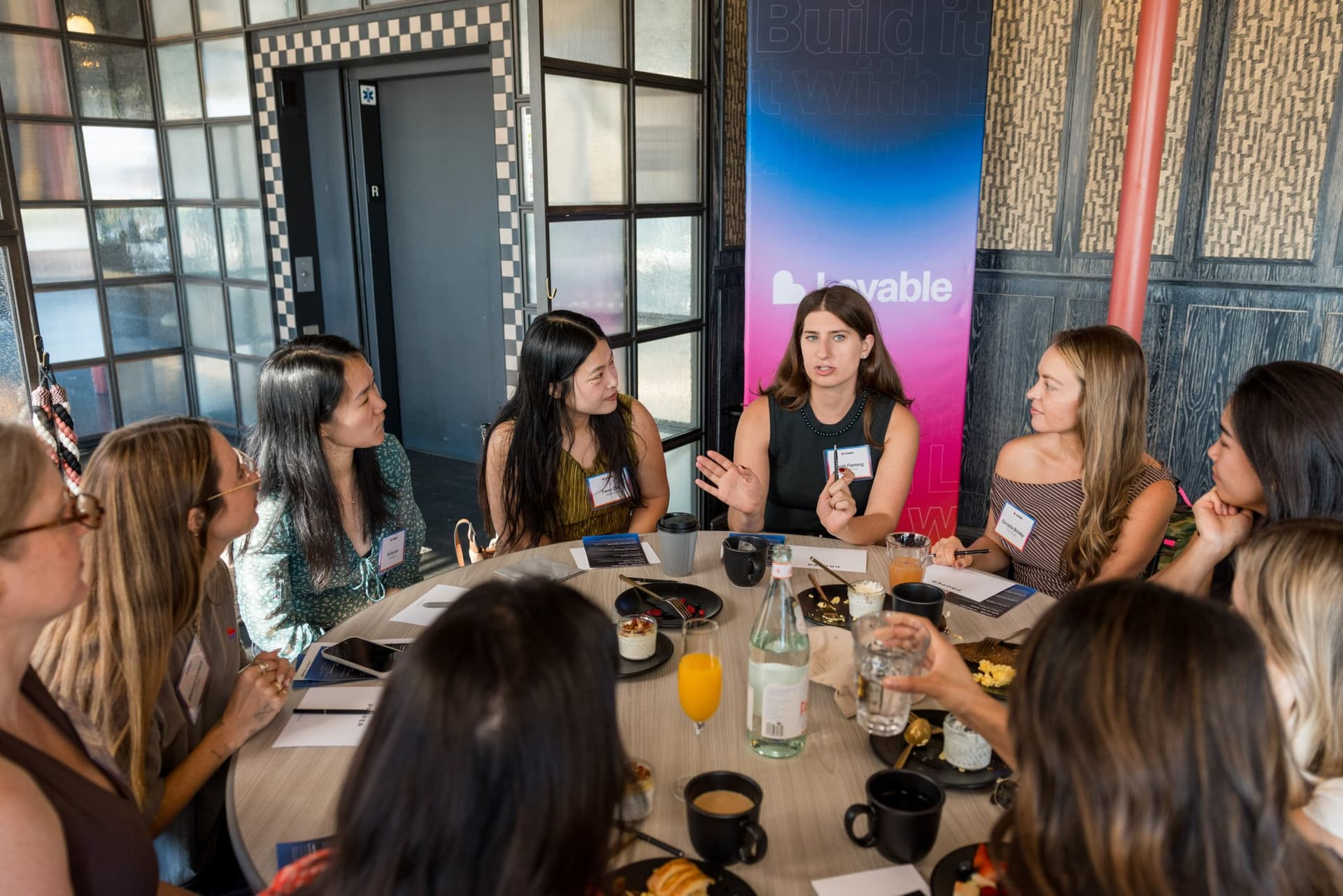 Guest leading the conversation at a roundtable in front of the Lovable banner at Lovable x Wispr Flow's Built on Her Terms brunch roundtable during SF Tech Week 2026 in San Francisco by JY Studio