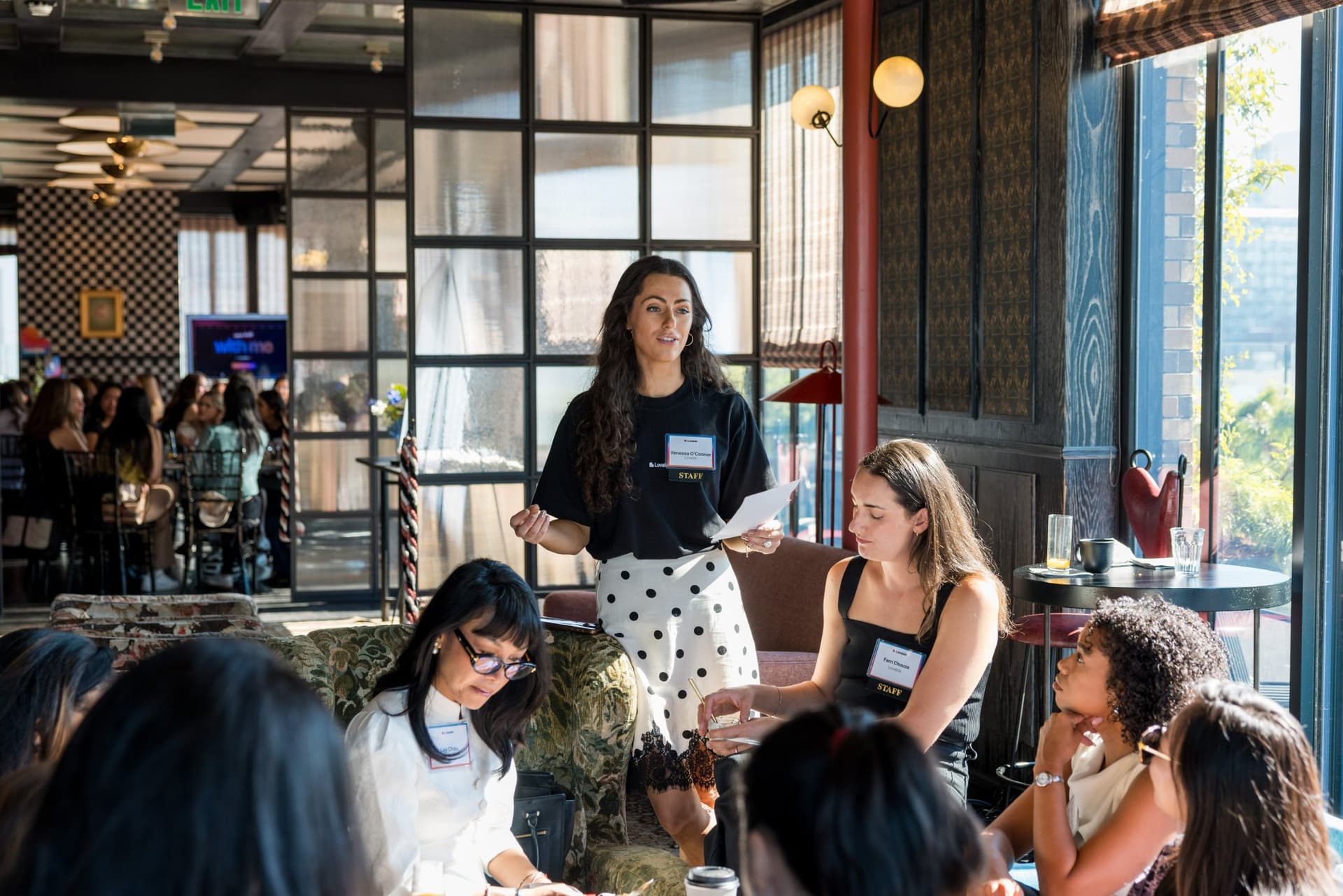 Facilitator standing to guide the lounge group discussion at Lovable x Wispr Flow's Built on Her Terms brunch roundtable during SF Tech Week 2026 in San Francisco by JY Studio