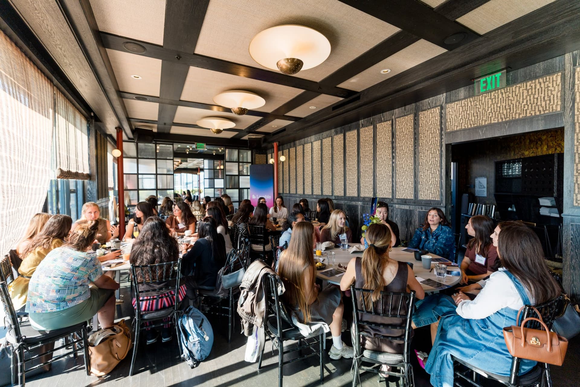 Wide shot of brunch tables filled with women builders and founders at Lovable x Wispr Flow's Built on Her Terms brunch roundtable during SF Tech Week 2026 in San Francisco by JY Studio