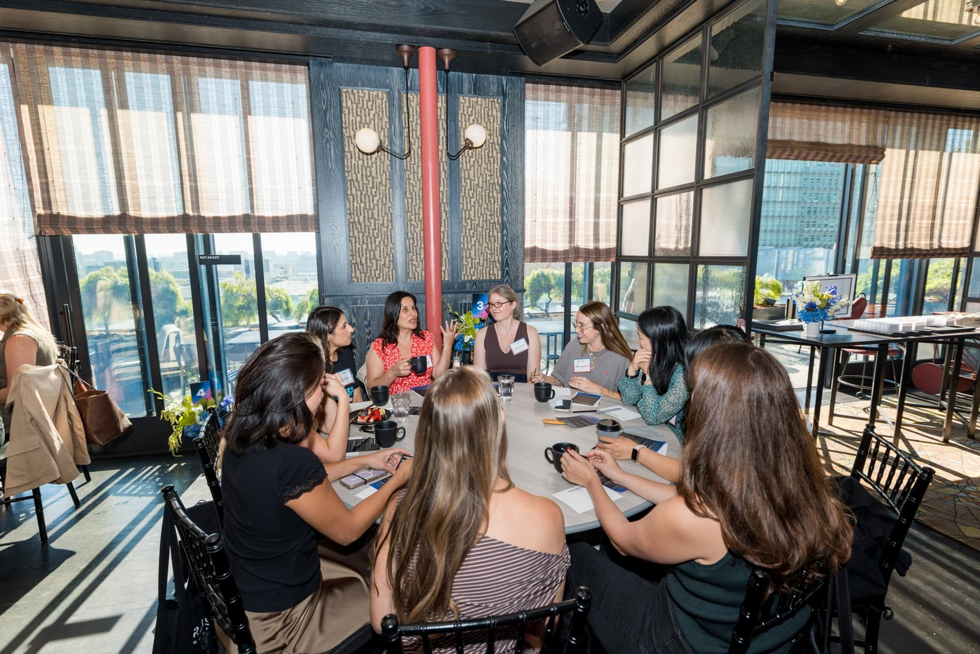 Sunlit roundtable by the floor-to-ceiling windows mid-discussion at Lovable x Wispr Flow's Built on Her Terms brunch roundtable during SF Tech Week 2026 in San Francisco by JY Studio