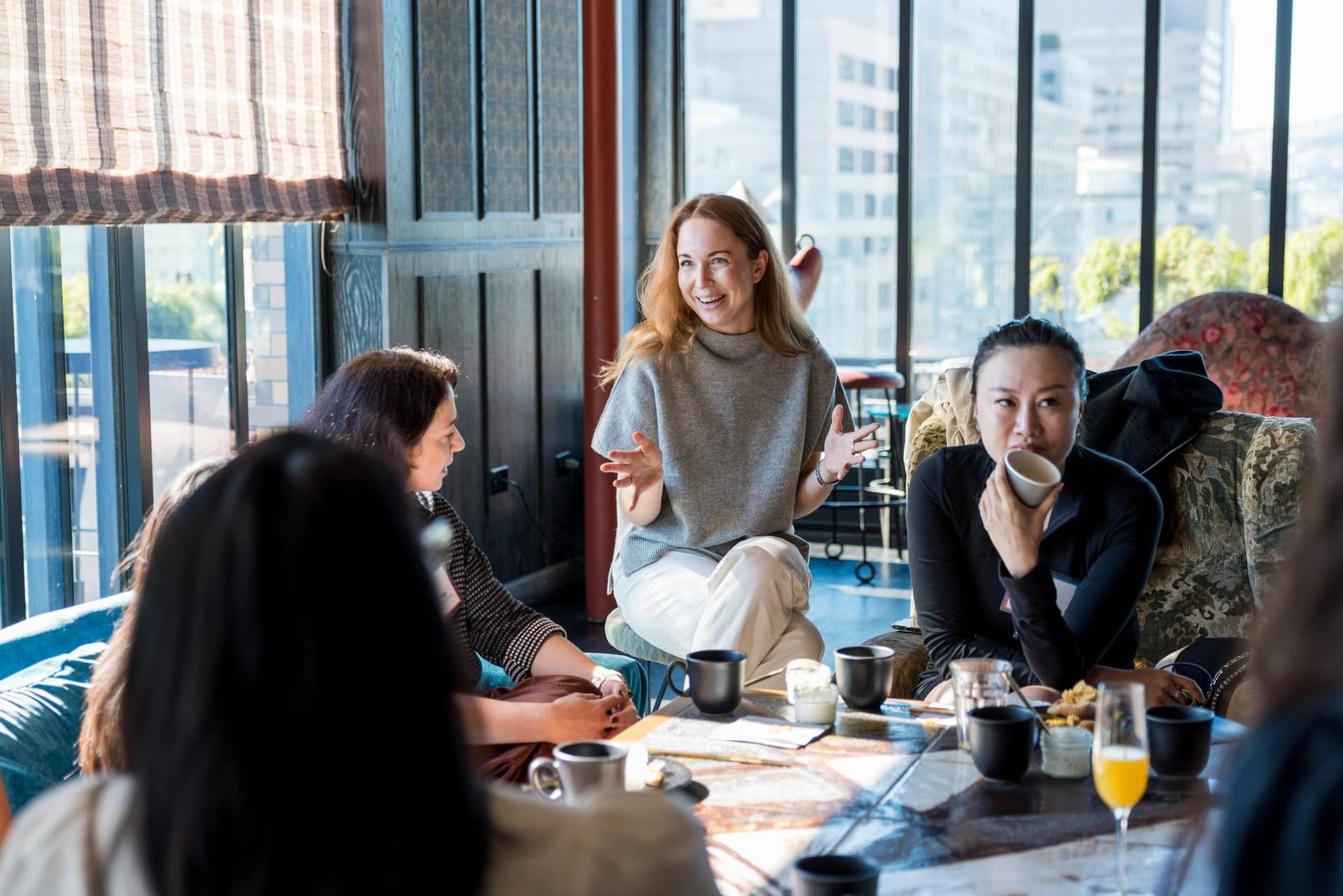 Two guests laughing over mimosas during the lounge conversation at Lovable x Wispr Flow's Built on Her Terms brunch roundtable during SF Tech Week 2026 in San Francisco by JY Studio