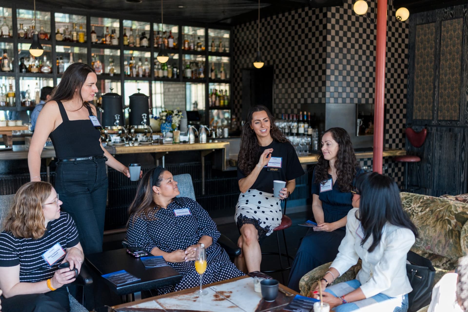 Facilitator standing beside the bar as the lounge group talks at Lovable x Wispr Flow's Built on Her Terms brunch roundtable during SF Tech Week 2026 in San Francisco by JY Studio