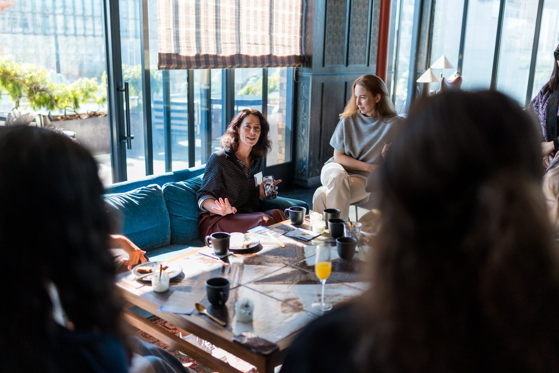 Guests in the window lounge discussing leading on their own terms at Lovable x Wispr Flow's Built on Her Terms brunch roundtable during SF Tech Week 2026 in San Francisco by JY Studio