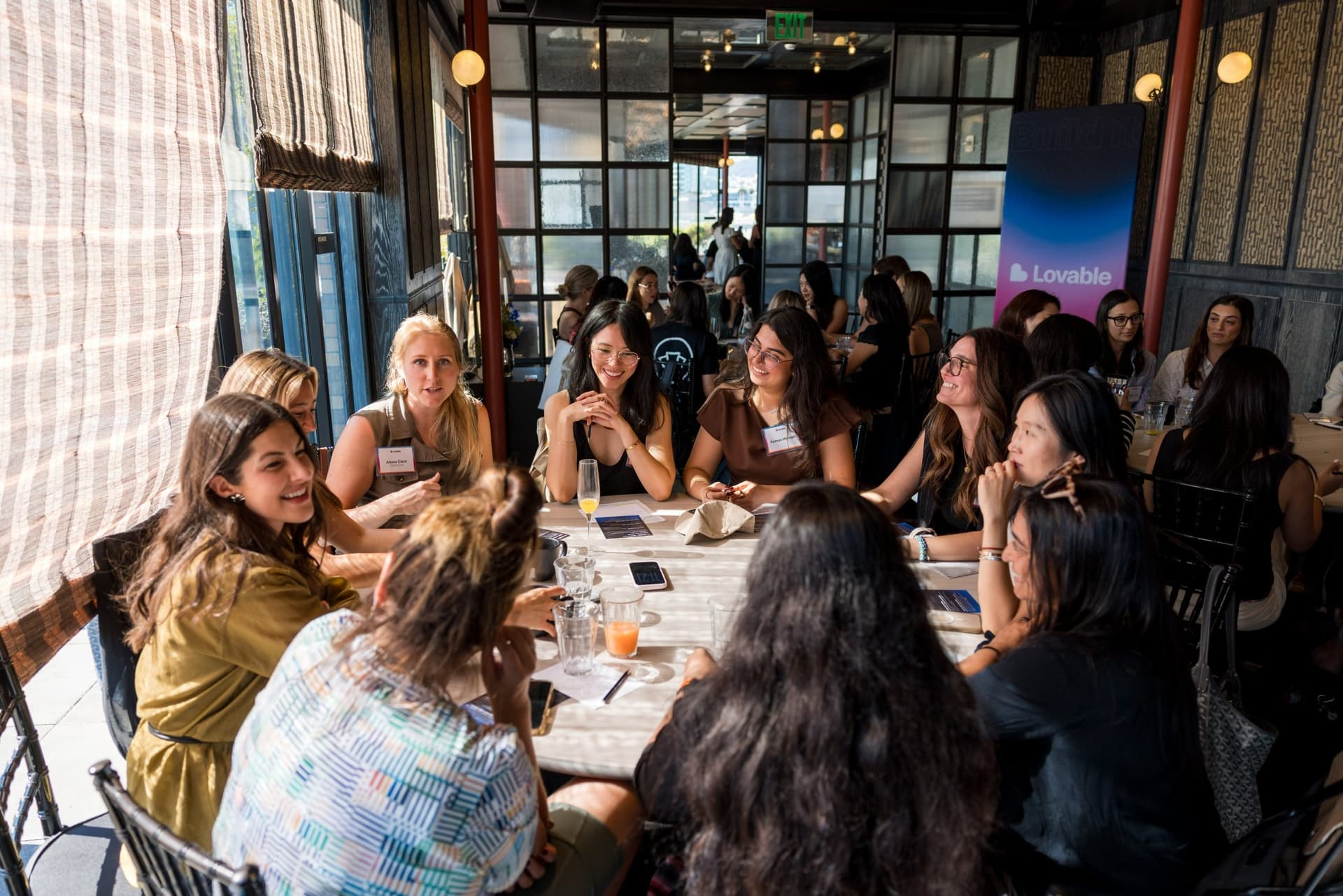 Roundtable guests laughing together at a crowded brunch table at Lovable x Wispr Flow's Built on Her Terms brunch roundtable during SF Tech Week 2026 in San Francisco by JY Studio