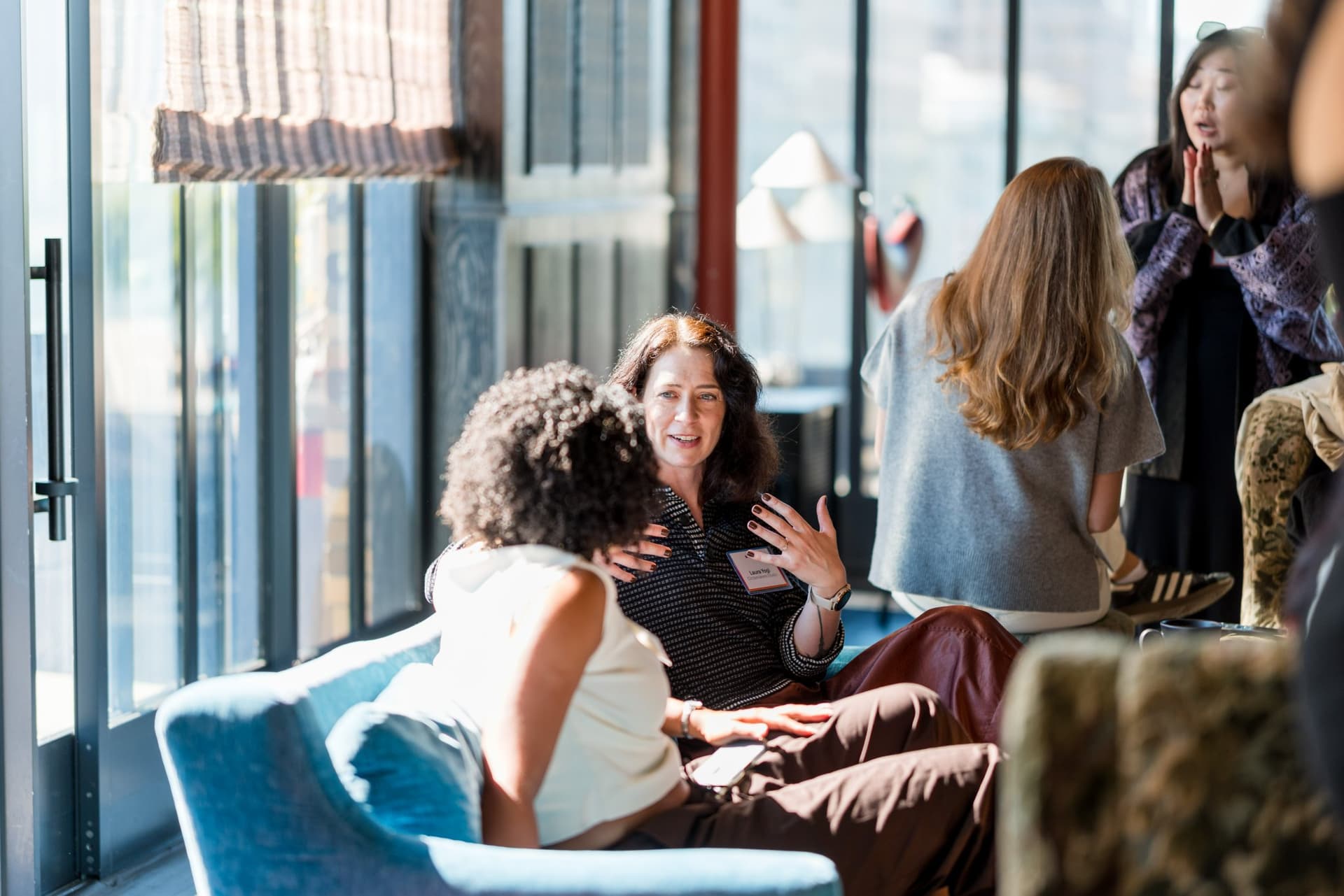 Guest gesturing while sharing her experience in the lounge discussion at Lovable x Wispr Flow's Built on Her Terms brunch roundtable during SF Tech Week 2026 in San Francisco by JY Studio