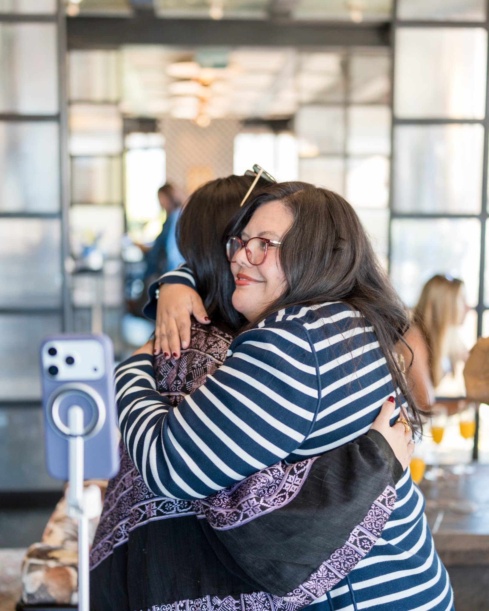 Two guests sharing a warm hug at the end of the brunch at Lovable x Wispr Flow's Built on Her Terms brunch roundtable during SF Tech Week 2026 in San Francisco by JY Studio