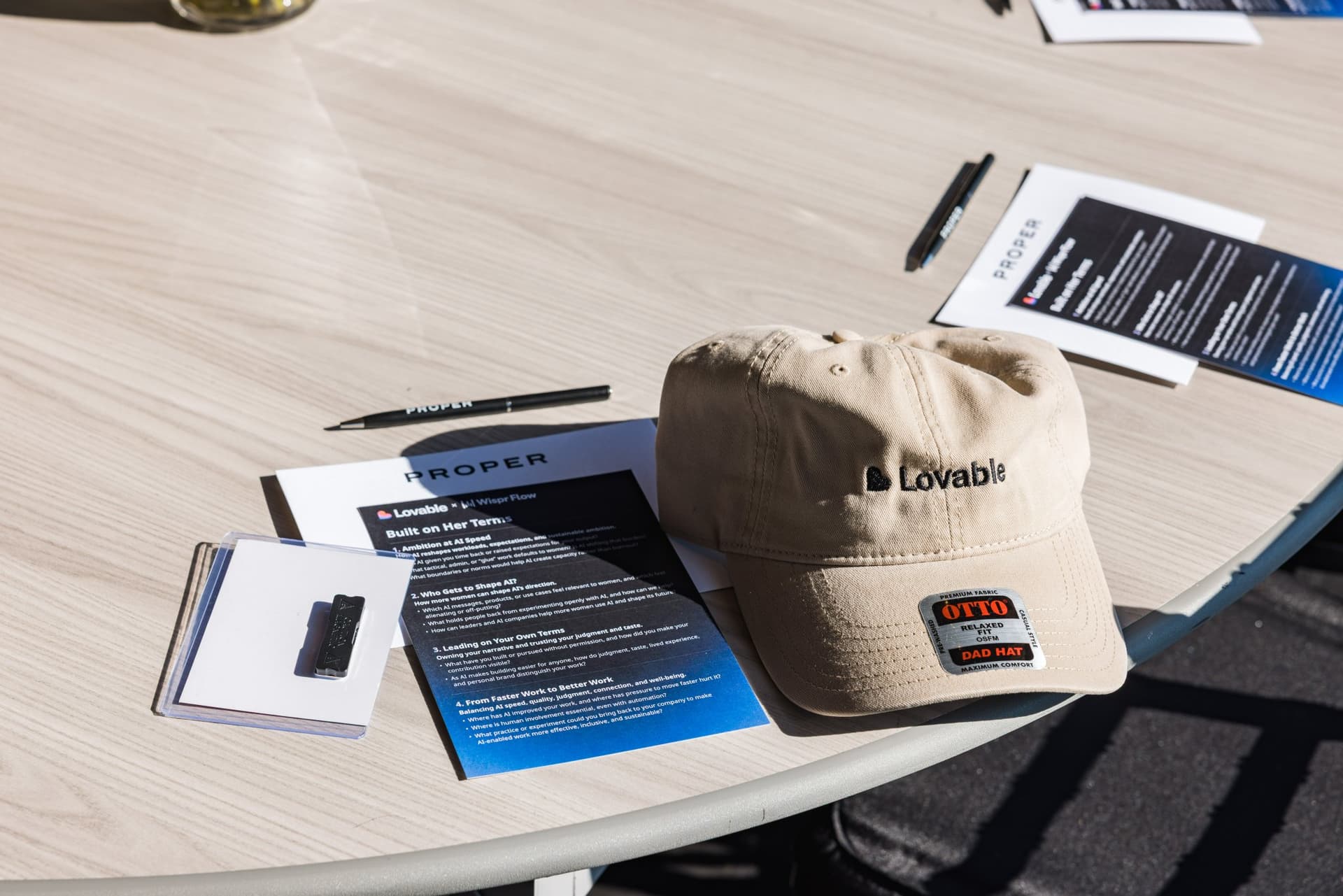 Lovable cap, discussion guide, and Proper pen left on a brunch table at Lovable x Wispr Flow's Built on Her Terms brunch roundtable during SF Tech Week 2026 in San Francisco by JY Studio