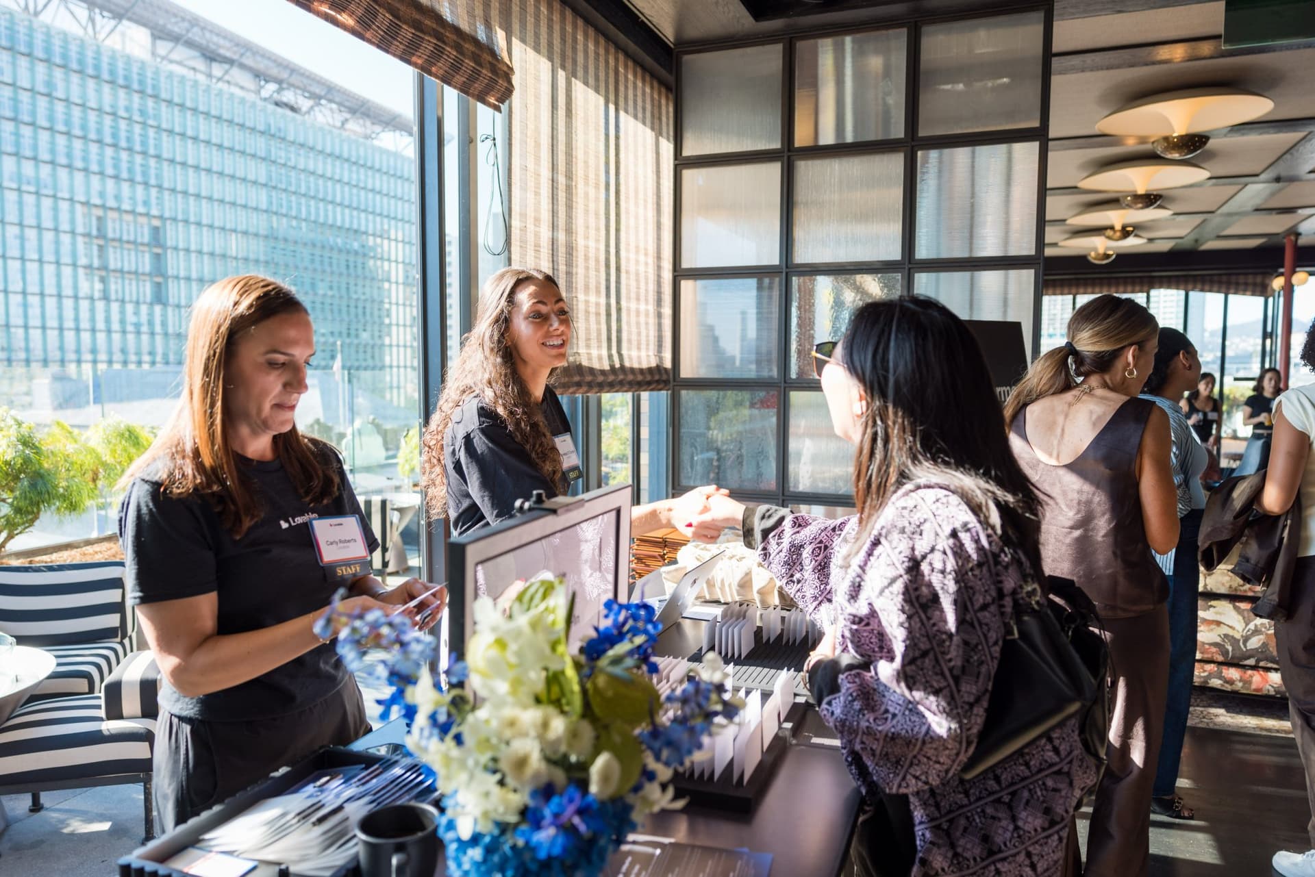 Lovable team welcoming guests at the sunlit check-in desk at Lovable x Wispr Flow's Built on Her Terms brunch roundtable during SF Tech Week 2026 in San Francisco by JY Studio
