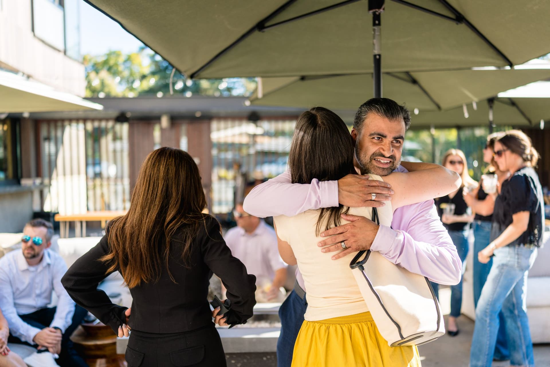 Guests laughing and toasting cocktails on the patio at the Magnus event in Palo Alto