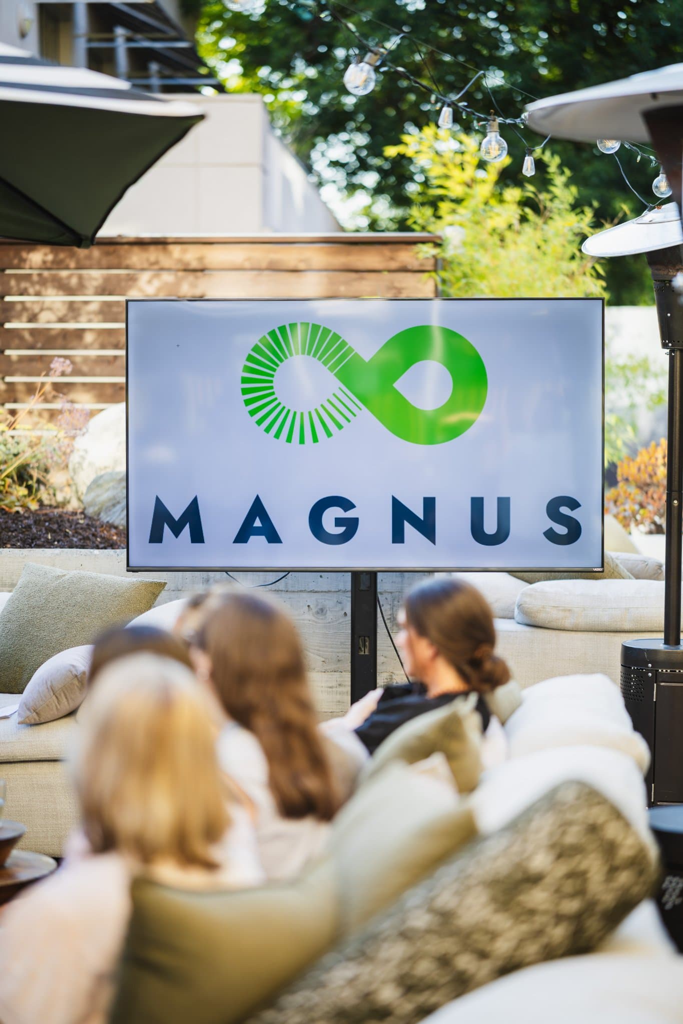 Members chatting near the patio heaters as the evening cools at the Magnus event in Palo Alto