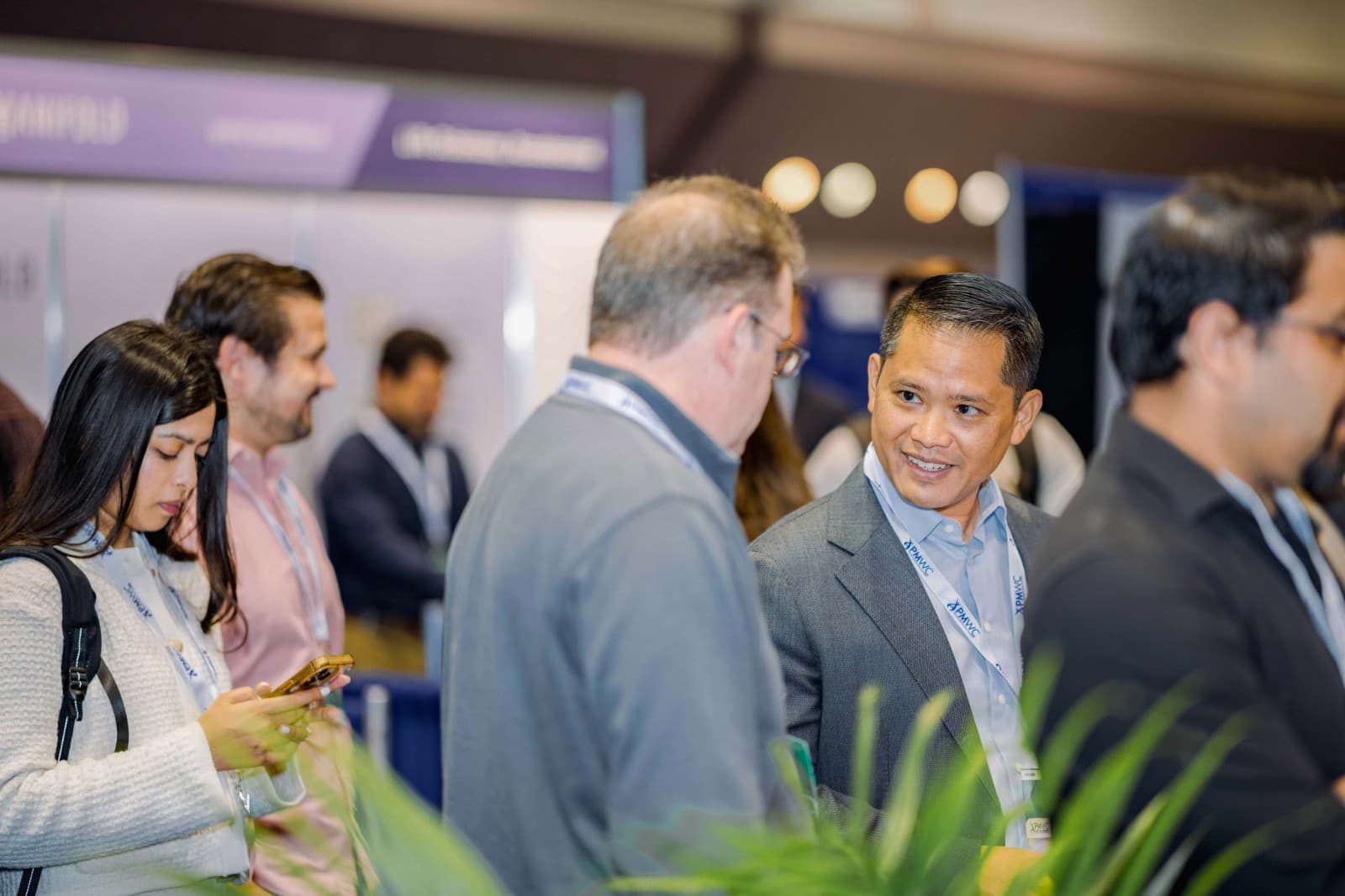 Biotech industry leaders networking at Novellia booth during PMWC 2026 in Bay Area by JY Studio