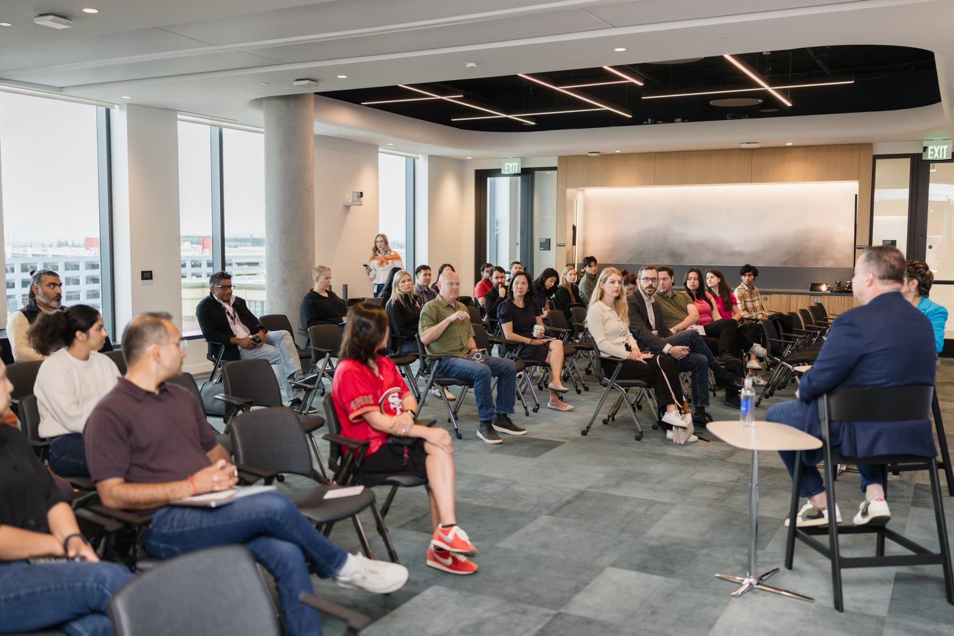 Wide view of the audience and fireside chat in the bright event space with floor-to-ceiling windows at the PwC x 49ers event at PwC Silicon Valley in San Jose by JY Studio