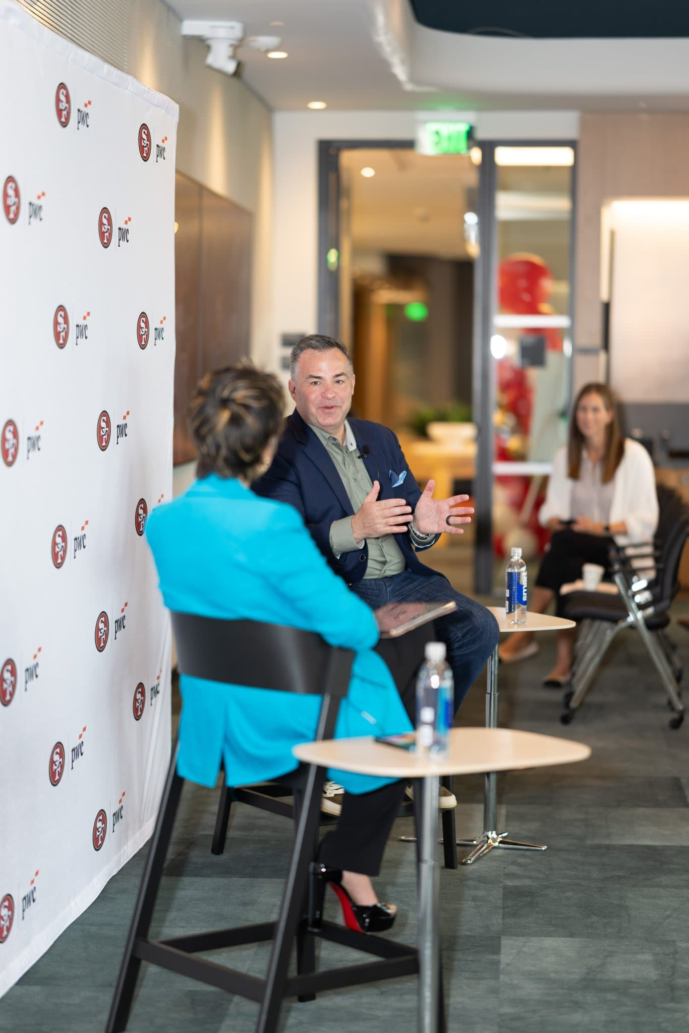 Side angle of the guest speaker talking with the moderator during the fireside chat at the PwC x 49ers event at PwC Silicon Valley in San Jose by JY Studio
