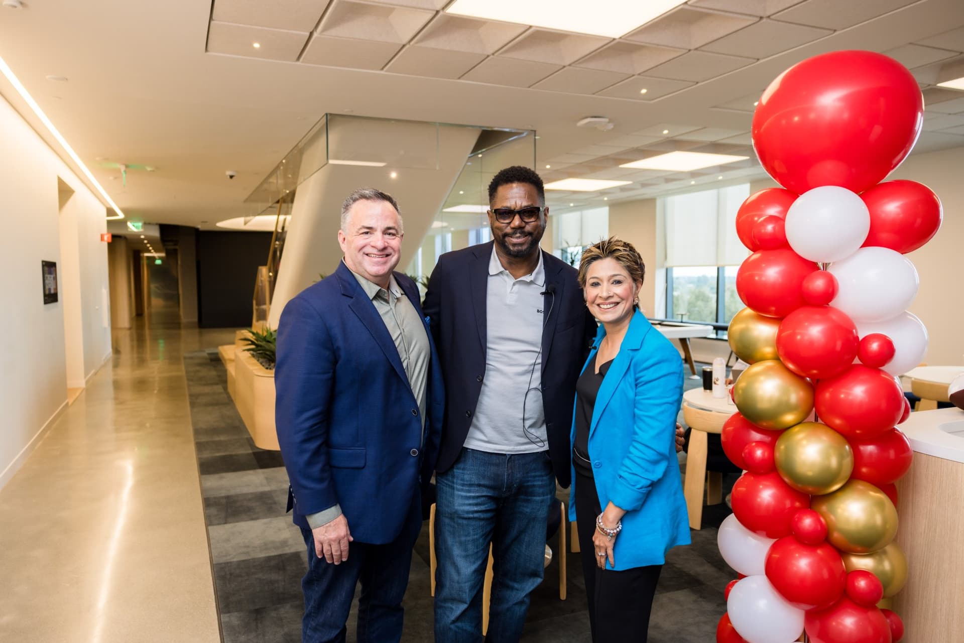 49ers legend, guest speaker and moderator posing beside red and gold balloons in the PwC office at the PwC x 49ers event at PwC Silicon Valley in San Jose by JY Studio