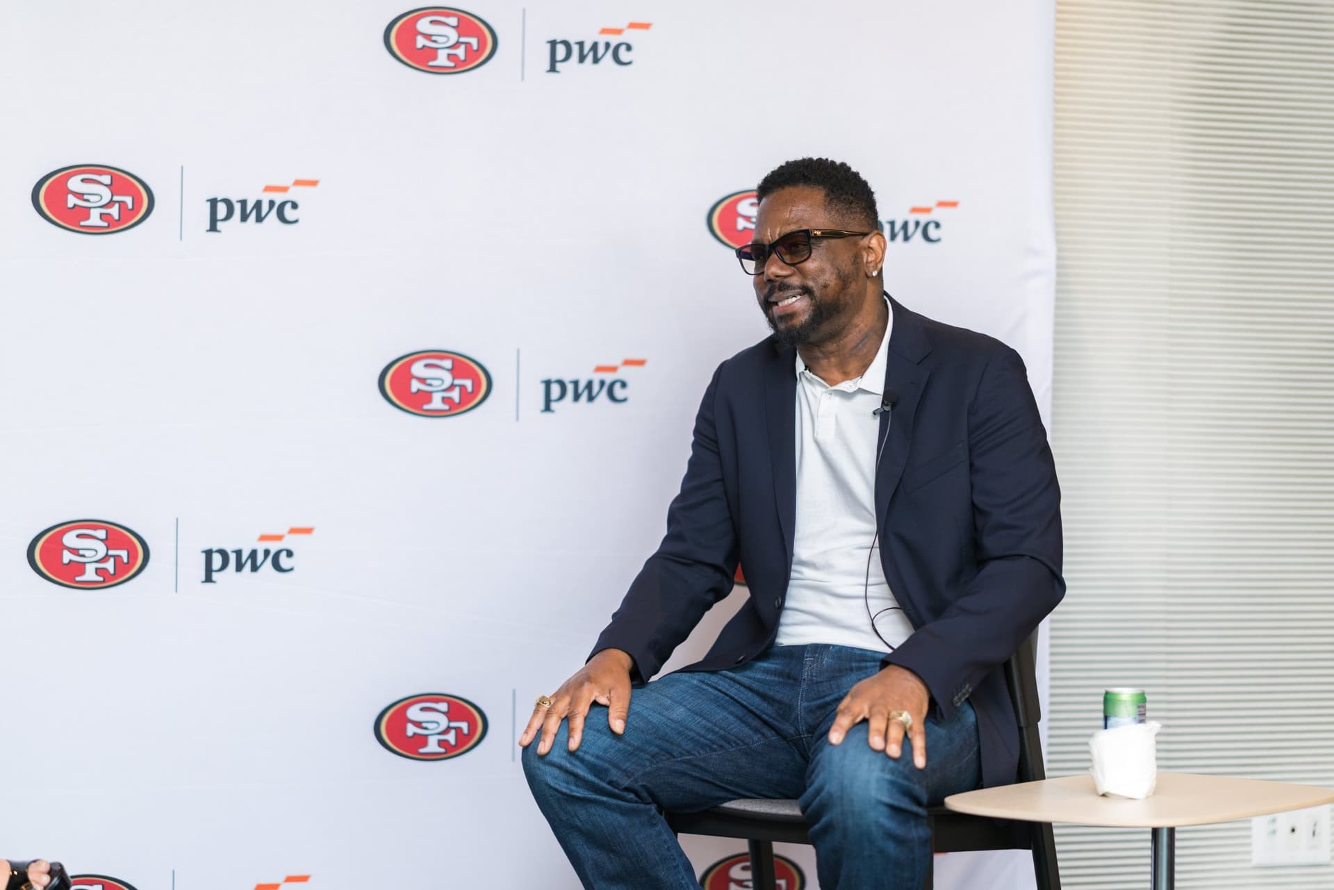 49ers legend smiling on stage in front of the 49ers and PwC step-and-repeat at the PwC x 49ers event at PwC Silicon Valley in San Jose by JY Studio