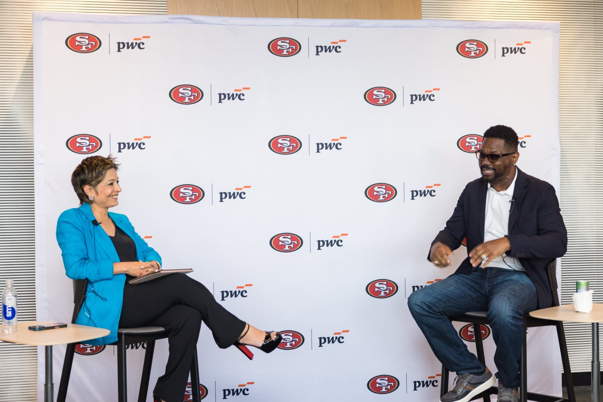 Moderator and 49ers legend sharing a laugh on stage during the fireside chat at the PwC x 49ers event at PwC Silicon Valley in San Jose by JY Studio