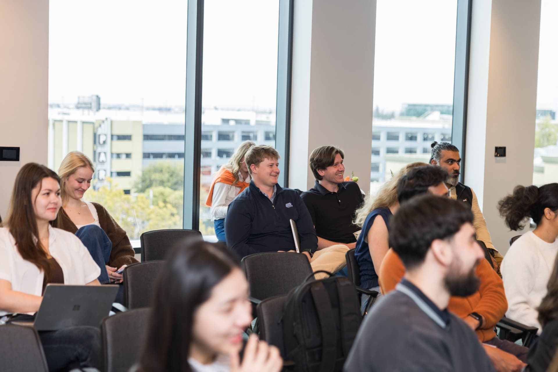 Attendees by the windows smiling during the fireside chat at the PwC x 49ers event at PwC Silicon Valley in San Jose by JY Studio