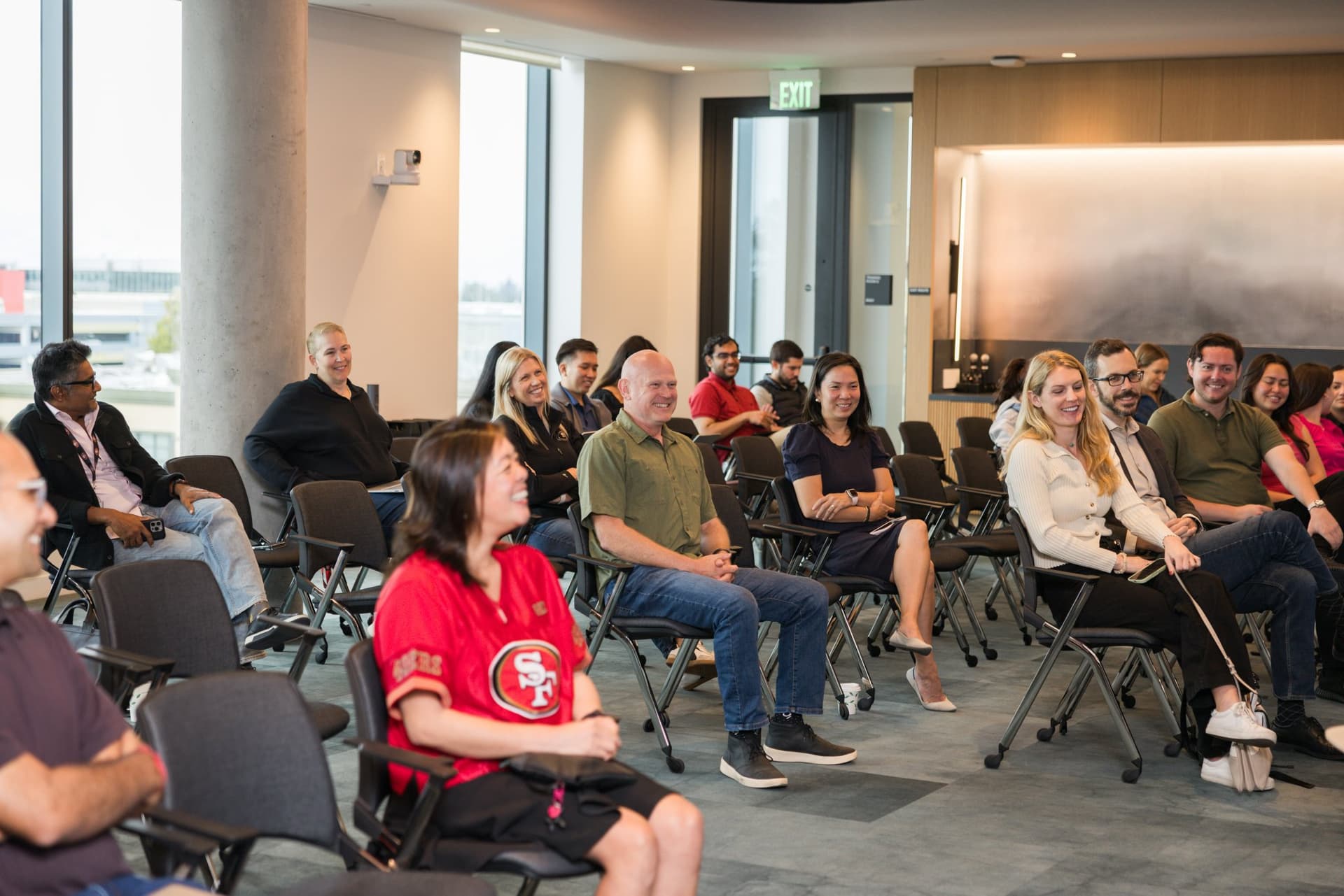 Audience smiling including a fan in a red 49ers jersey at the PwC x 49ers event at PwC Silicon Valley in San Jose by JY Studio