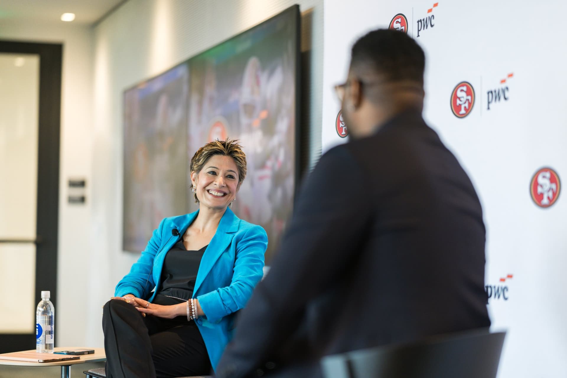 Moderator smiling during the fireside chat beside the 49ers legend at the PwC x 49ers event at PwC Silicon Valley in San Jose by JY Studio