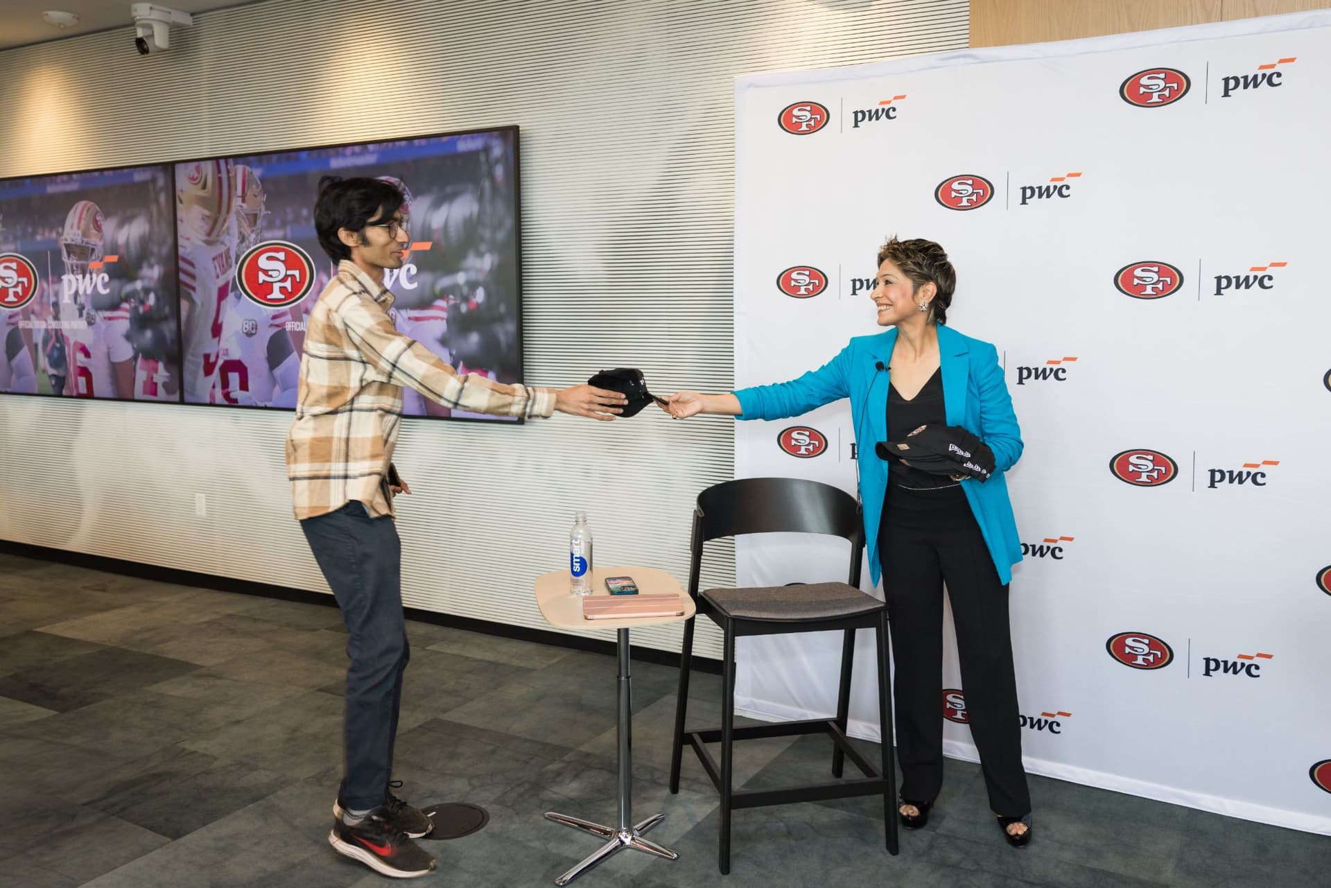 Attendee receiving a 49ers cap from the moderator during the raffle giveaway at the PwC x 49ers event at PwC Silicon Valley in San Jose by JY Studio