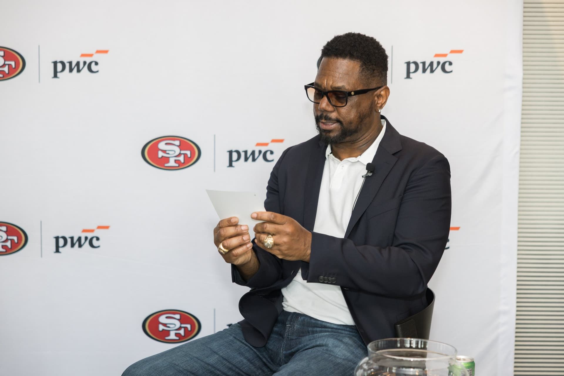 49ers legend reading a raffle winner card on stage at the PwC x 49ers event at PwC Silicon Valley in San Jose by JY Studio