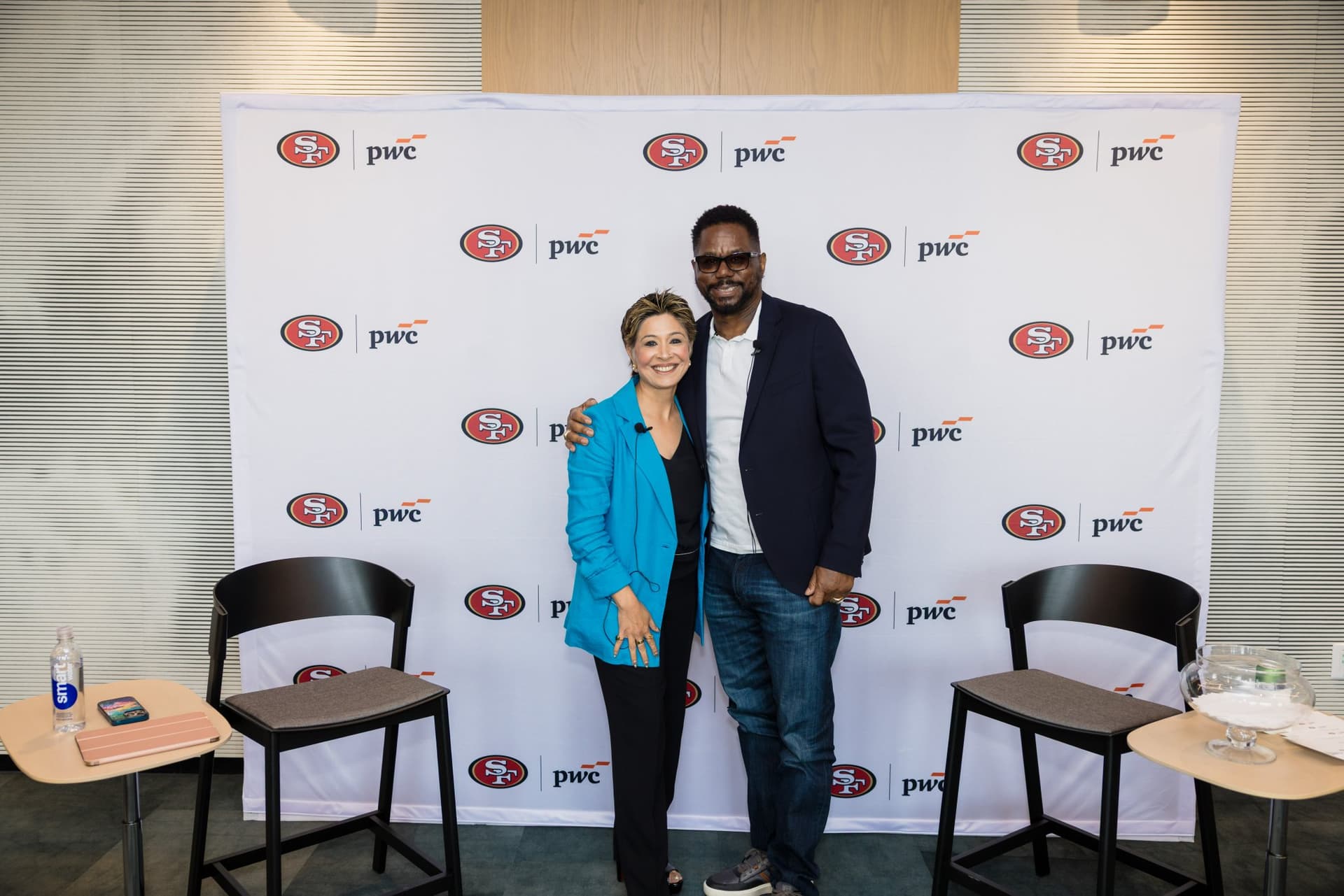 Moderator and 49ers legend posing together on stage after the fireside chat at the PwC x 49ers event at PwC Silicon Valley in San Jose by JY Studio