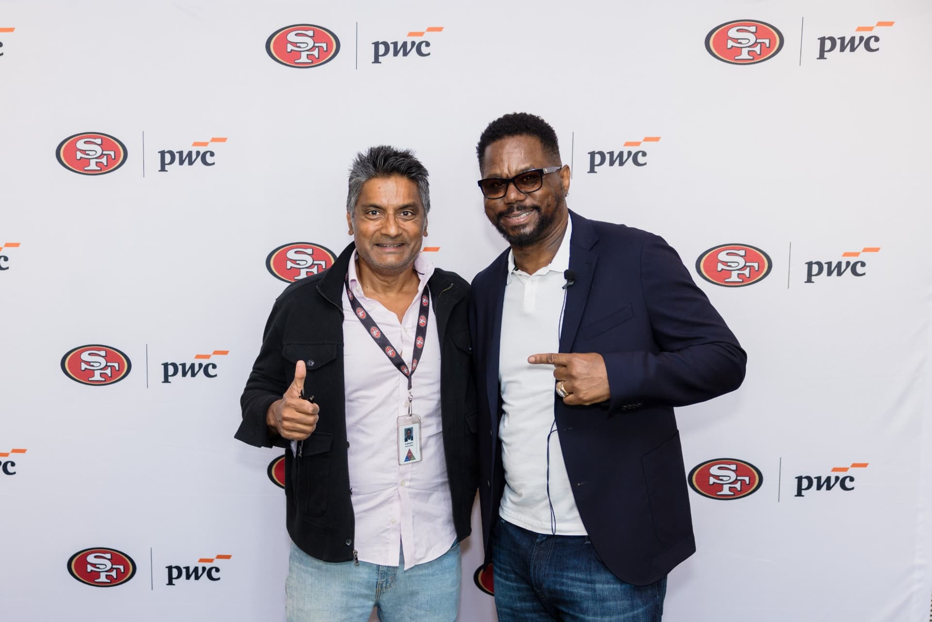 Attendee giving a thumbs up with the 49ers legend at the step-and-repeat at the PwC x 49ers event at PwC Silicon Valley in San Jose by JY Studio