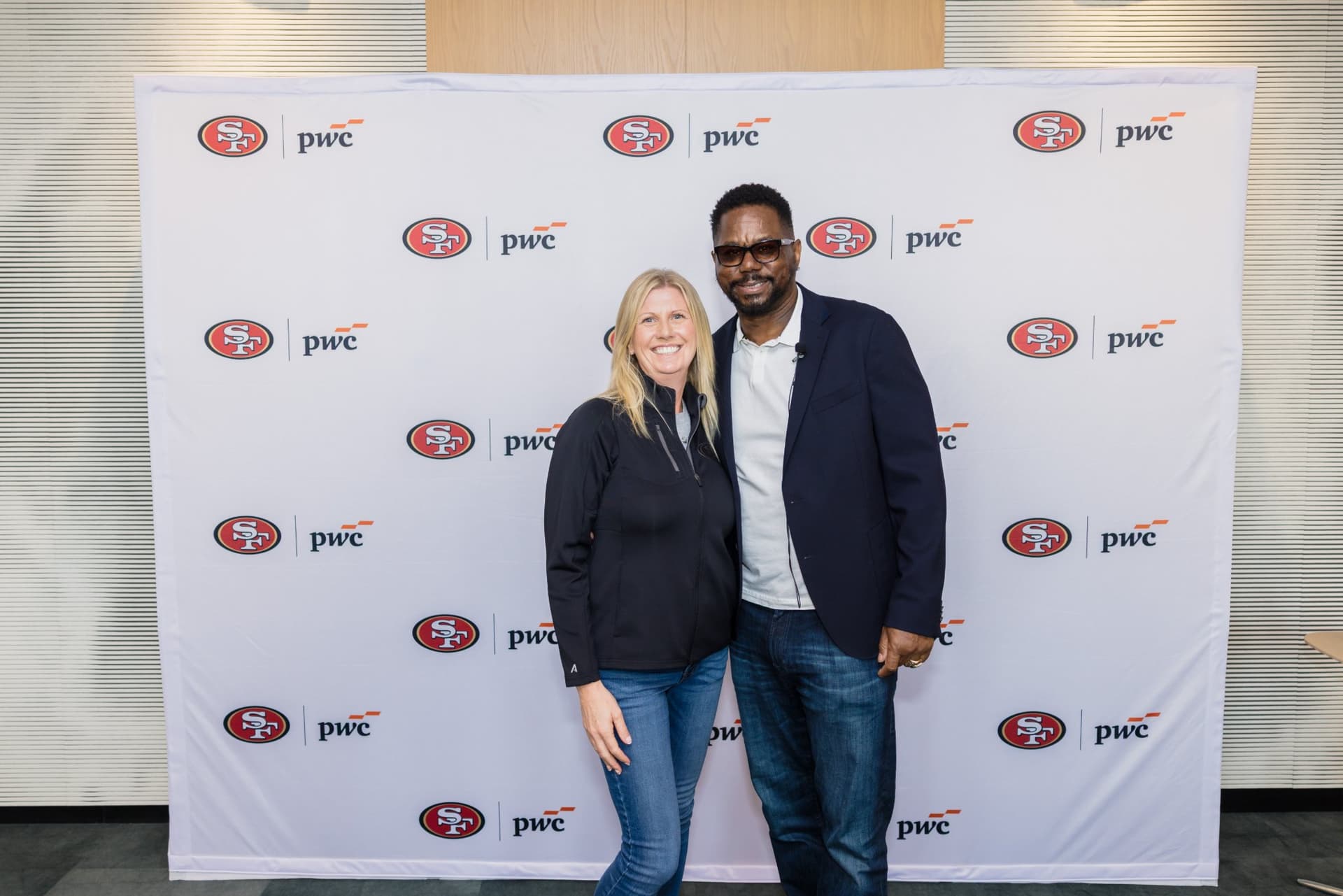 Attendee posing with the 49ers legend at the step-and-repeat at the PwC x 49ers event at PwC Silicon Valley in San Jose by JY Studio
