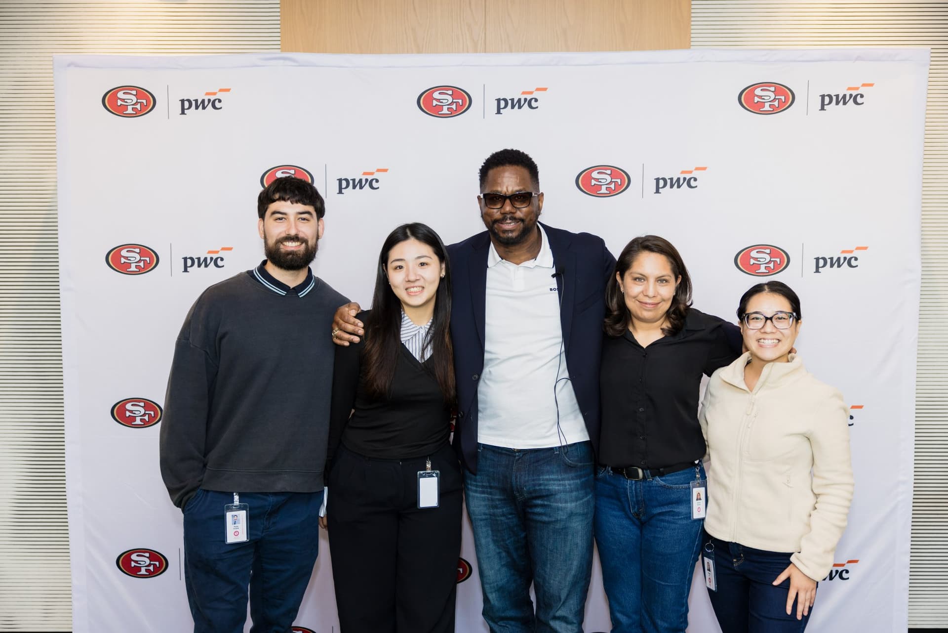 Group of PwC team members posing with the 49ers legend at the step-and-repeat at the PwC x 49ers event at PwC Silicon Valley in San Jose by JY Studio